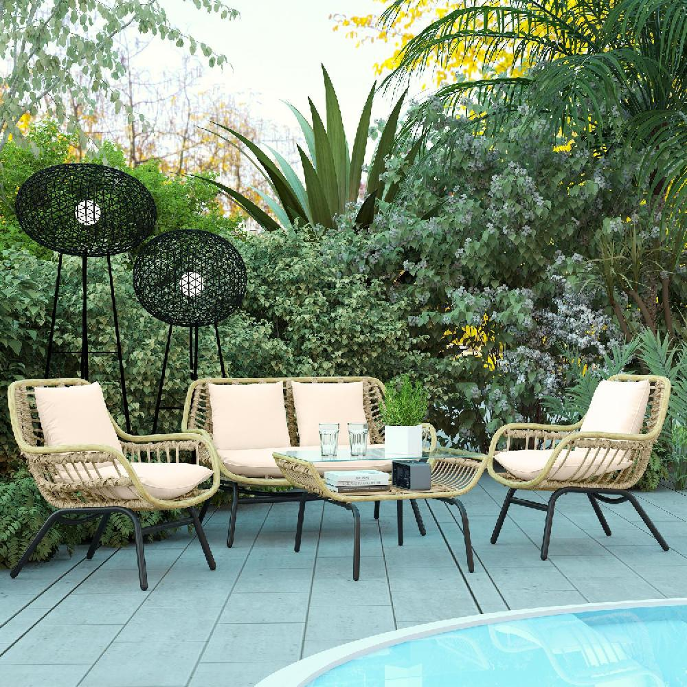 Salotto da giardino in vimini con cuscini beige chiaro, tavolino in vetro e lanterne.