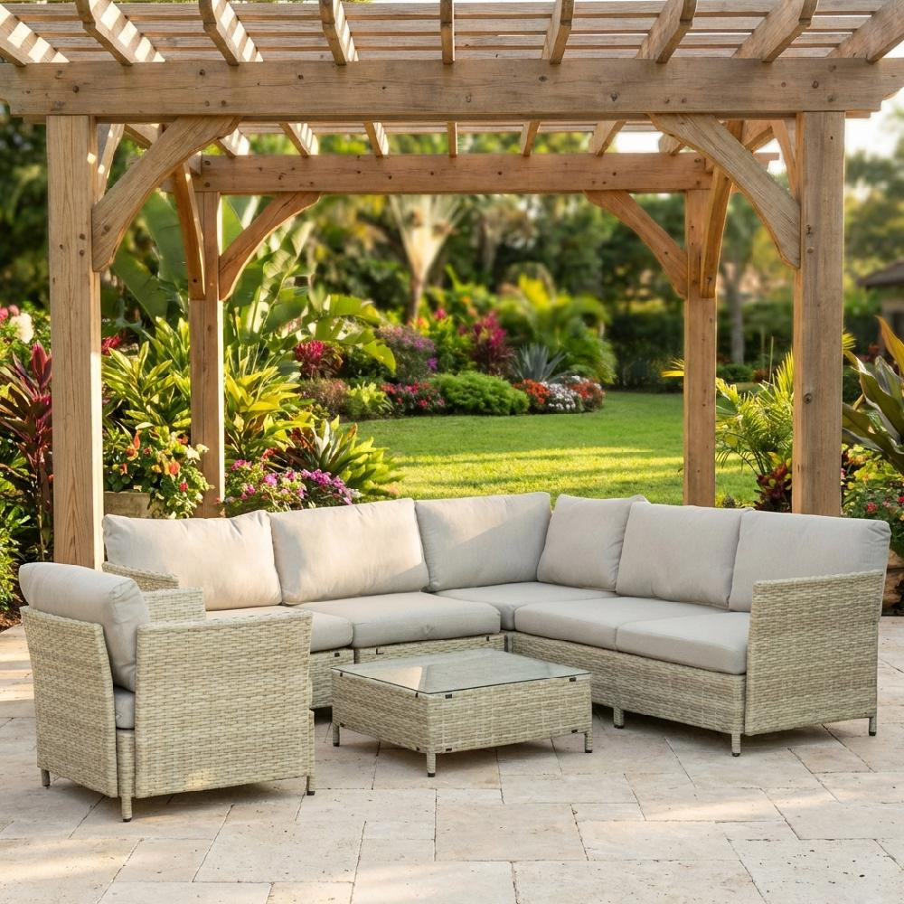 Un set di mobili da esterno in rattan beige con divano componibile, poltrona e tavolino sotto un pergolato di legno.