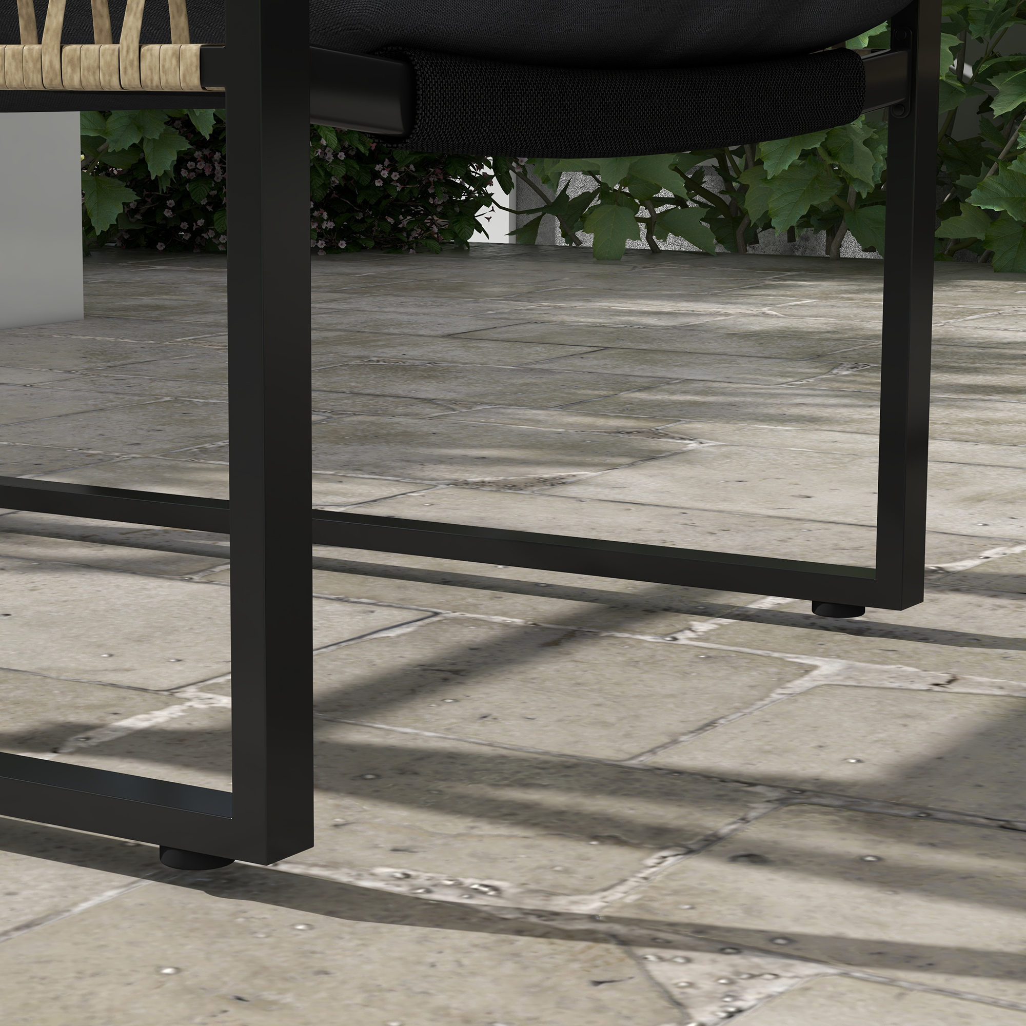 Gambe di sedia in metallo nero su un patio pavimentato con piante verdi sullo sfondo.