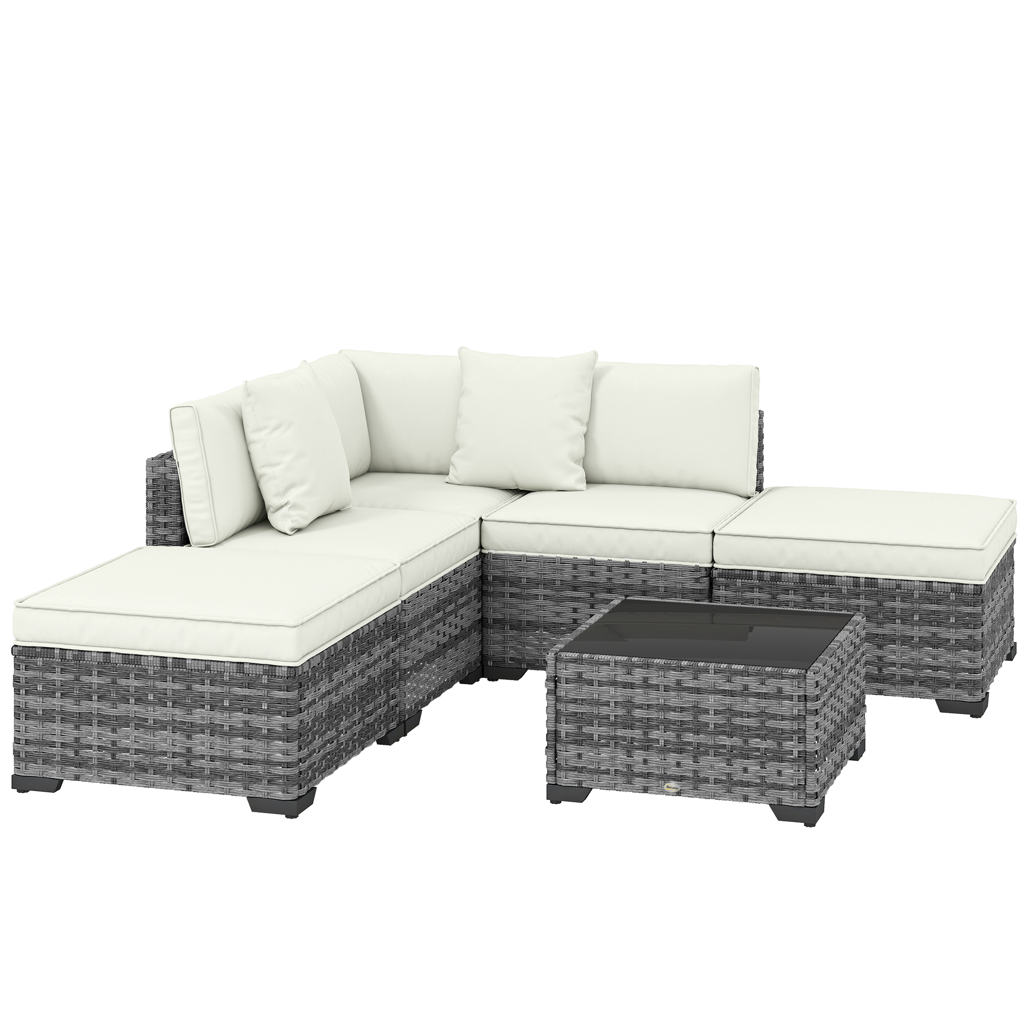 Divano componibile in rattan grigio con cuscini bianchi e tavolino in vetro.
