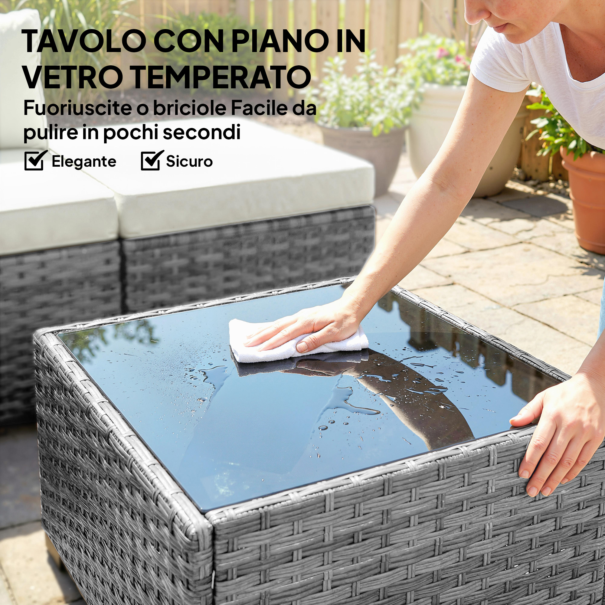 Una mano pulisce un tavolo in vetro bagnato con un panno bianco su base in rattan.