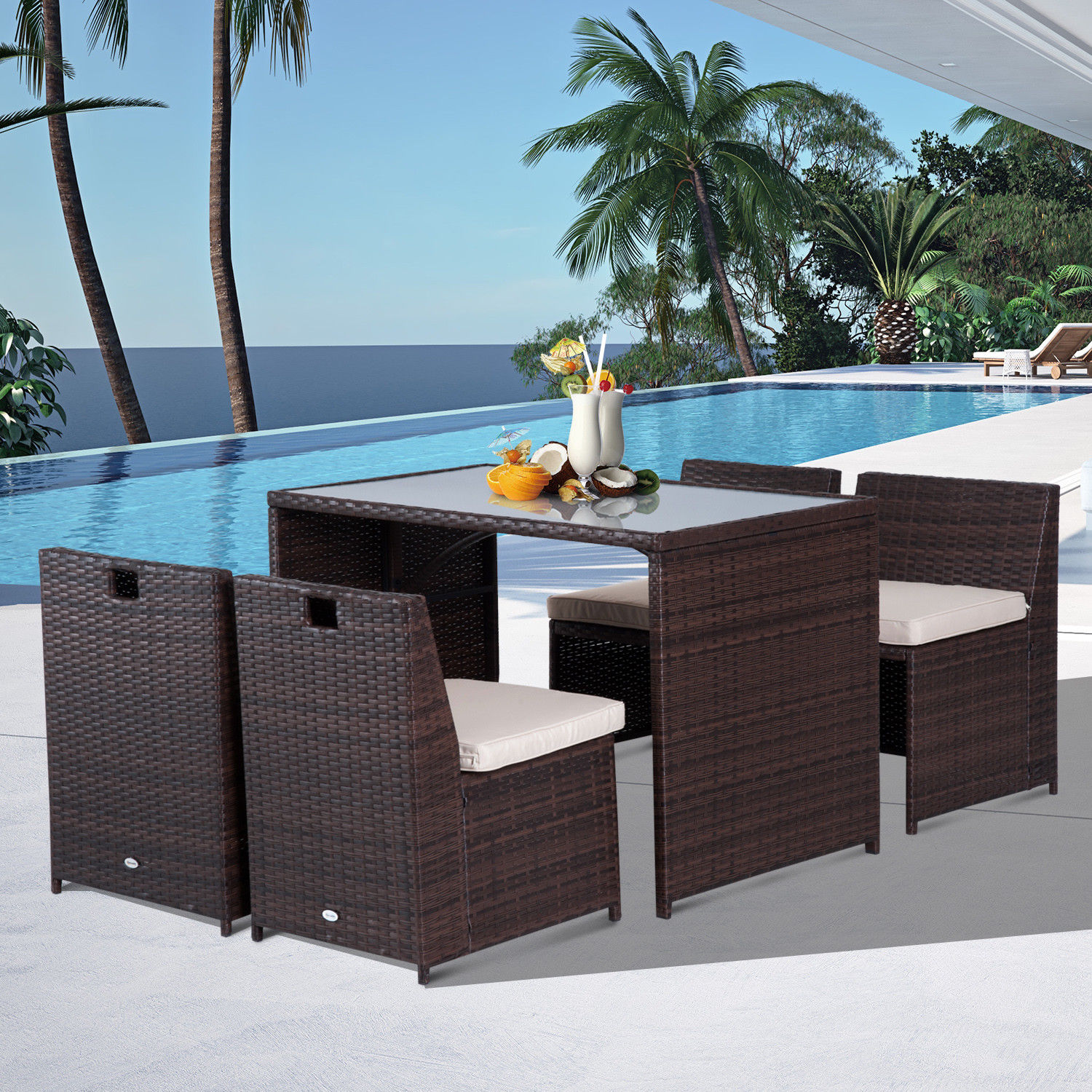 Un set da tavolo in rattan marrone con piano in vetro e quattro sedie vicino a una piscina.