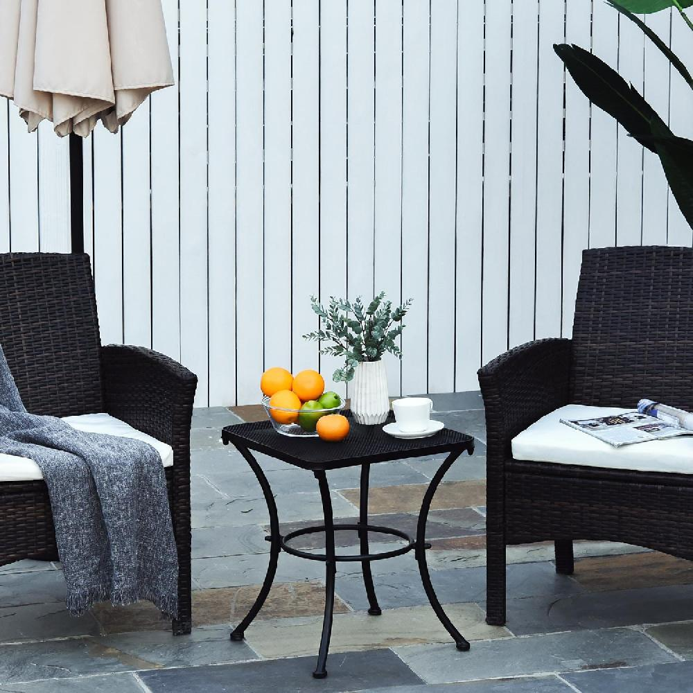 Due poltrone in rattan marrone con cuscini e coperta, tavolino con frutta e tazza.