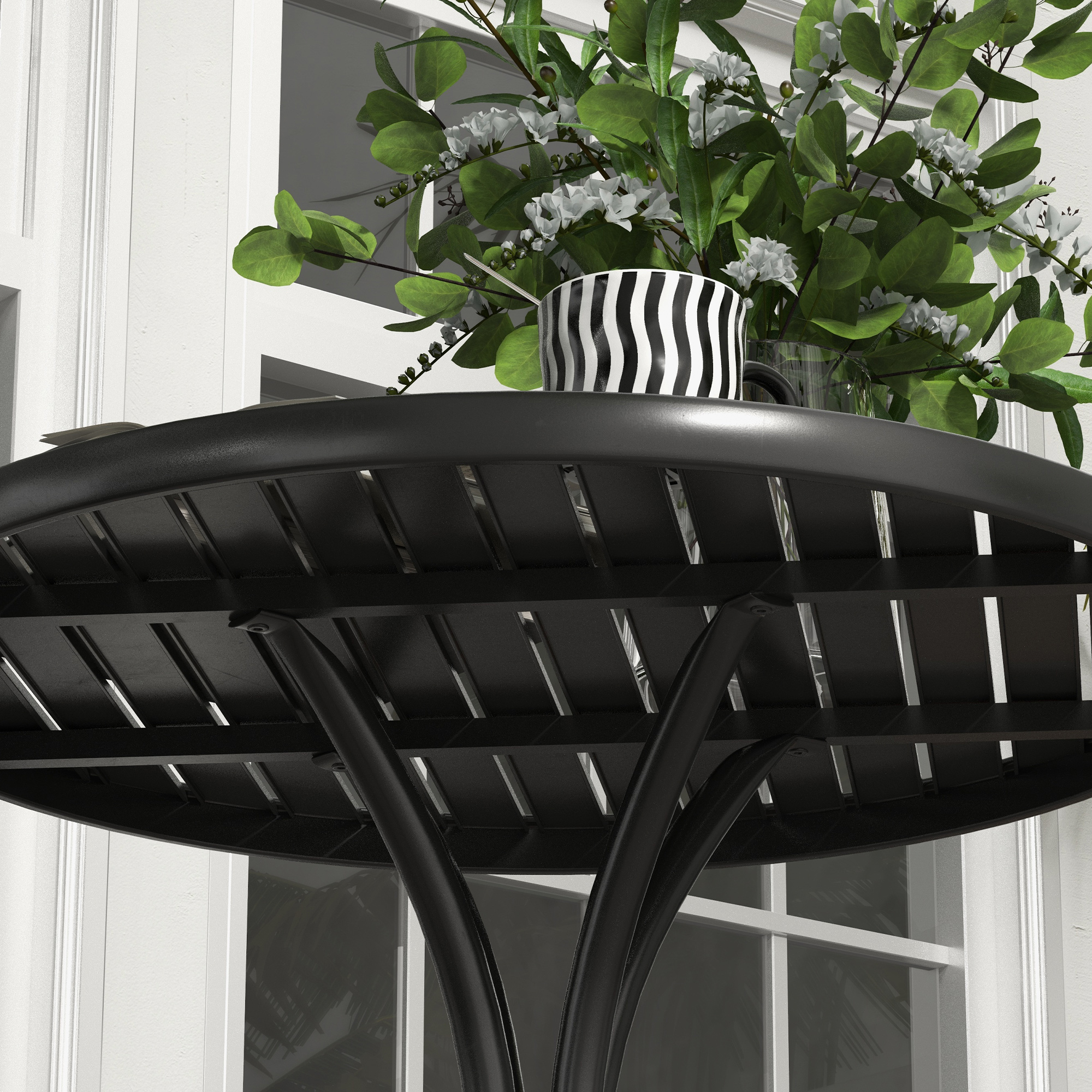 Un tavolo nero con decorazioni floreali e una tazza a strisce davanti a una finestra.