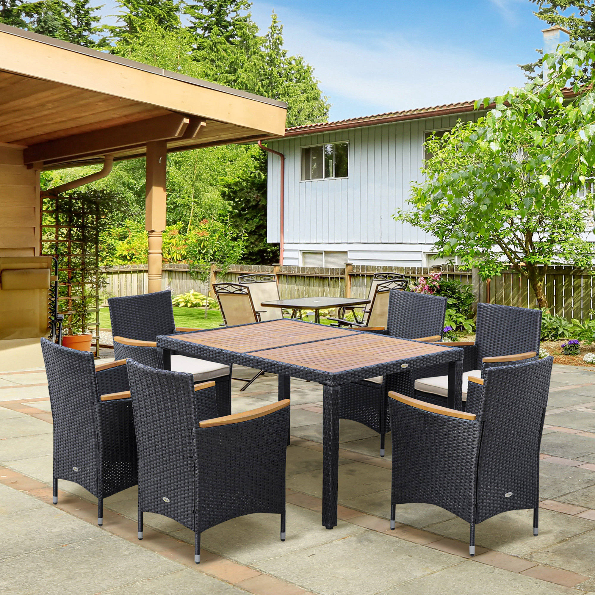 Un tavolo da pranzo in rattan scuro con otto sedie su un patio pavimentato.