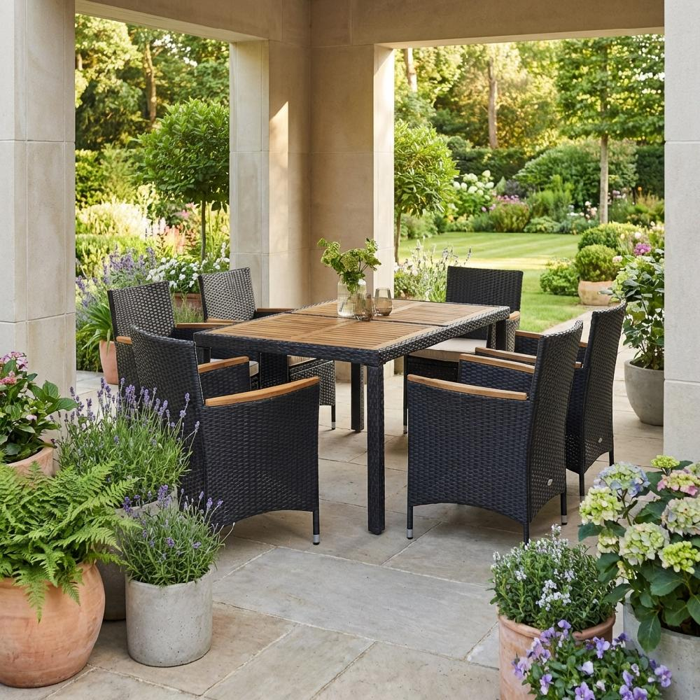 Set da pranzo da patio con sedie in rattan nero e tavolo in legno, circondato da giardino.