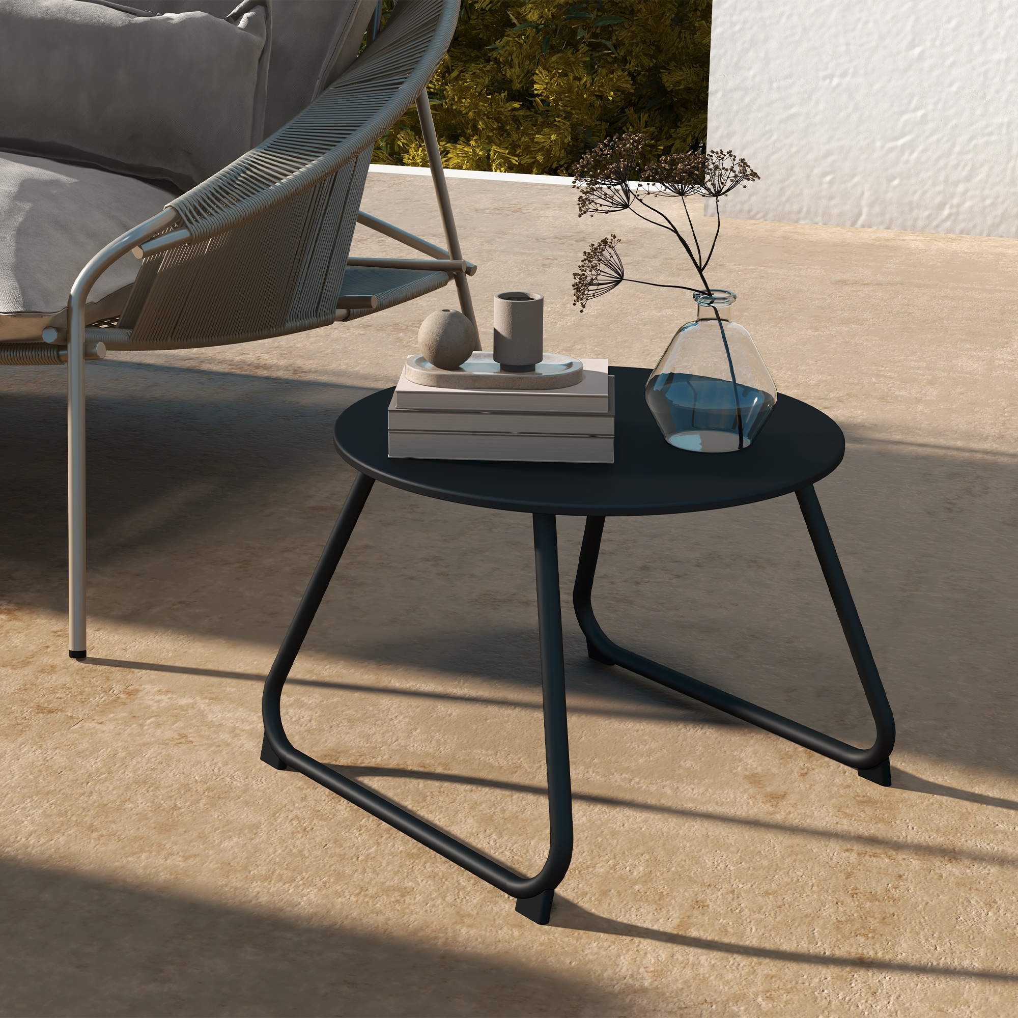 Un tavolino rotondo nero con oggetti decorativi e una sedia da esterno.