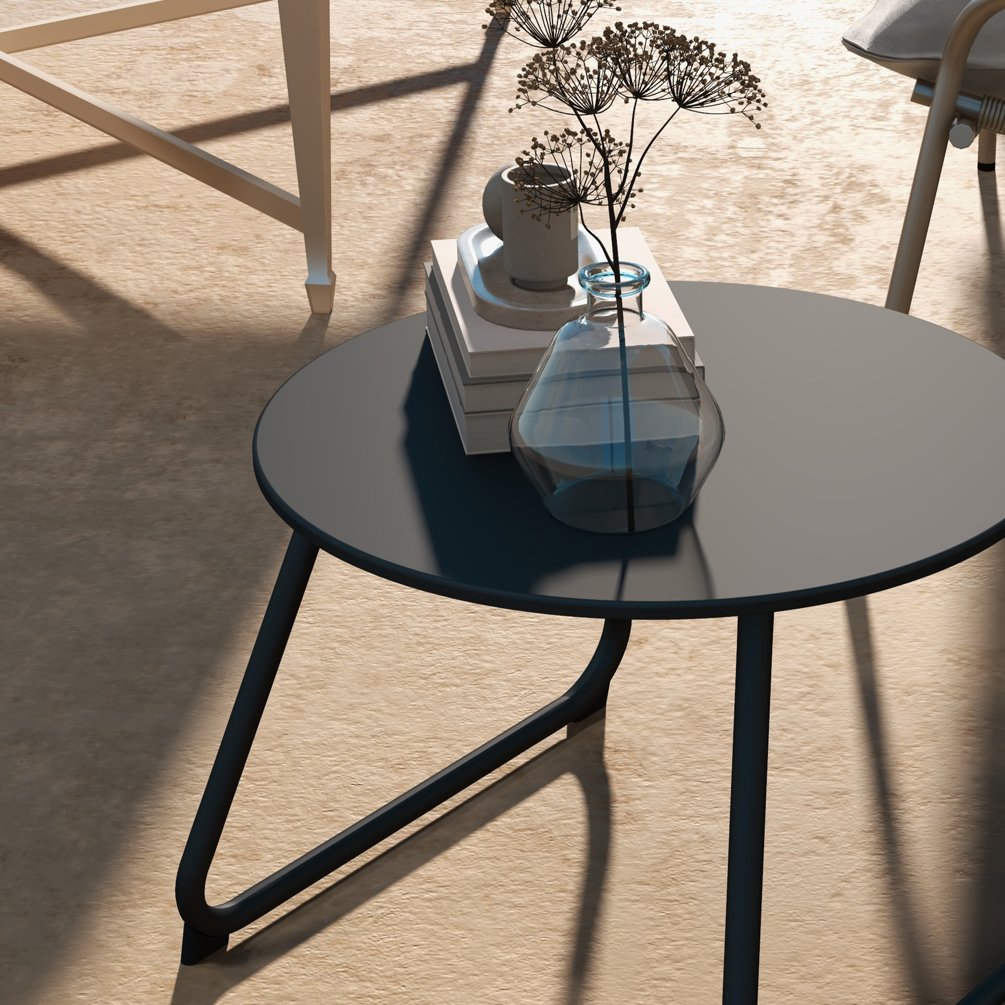 Tavolo rotondo con vaso di vetro, libri e tazza. Si vede il sole all'esterno.