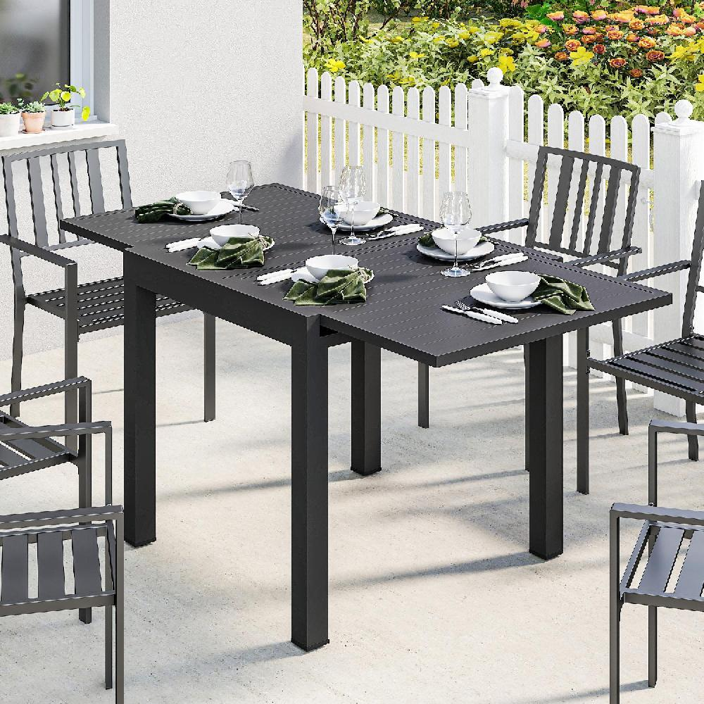Un tavolo da pranzo scuro per esterni apparecchiato per quattro, con sedie su un patio.