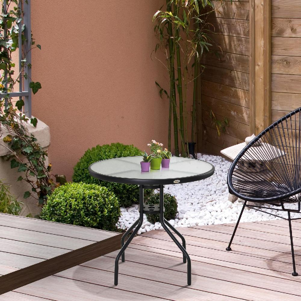 Un tavolo da patio con piano in vetro e piante si trova su un ponte di legno accanto a una sedia.