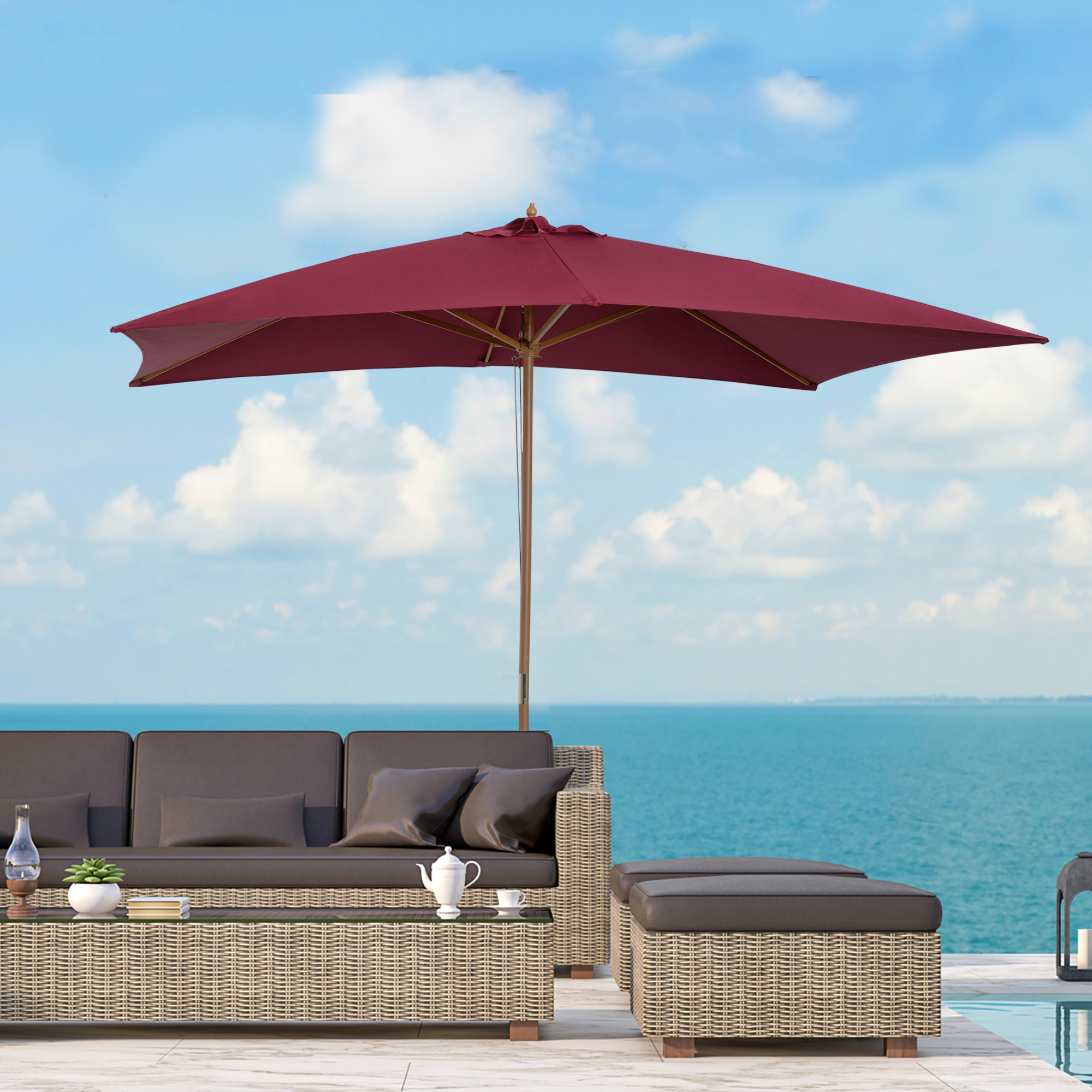 Divano in rattan marrone, tavolino con teiera e libro, ombrellone rosso.
