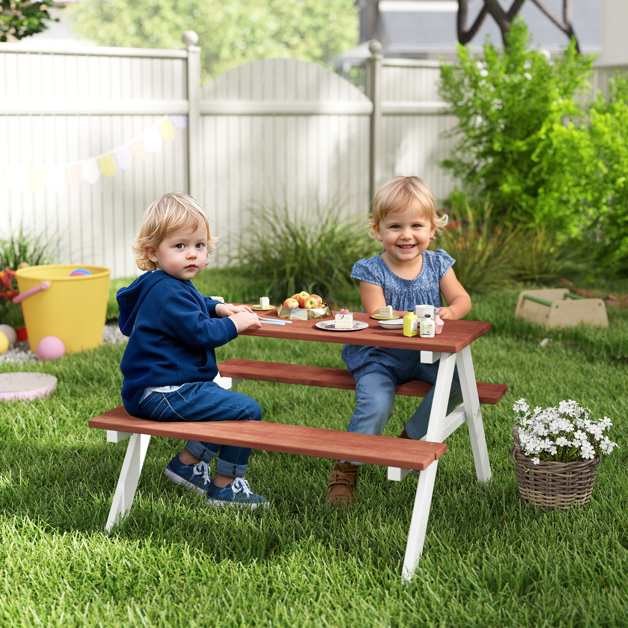 Due bambini giocano a un tavolo da picnic all'aperto su un prato.