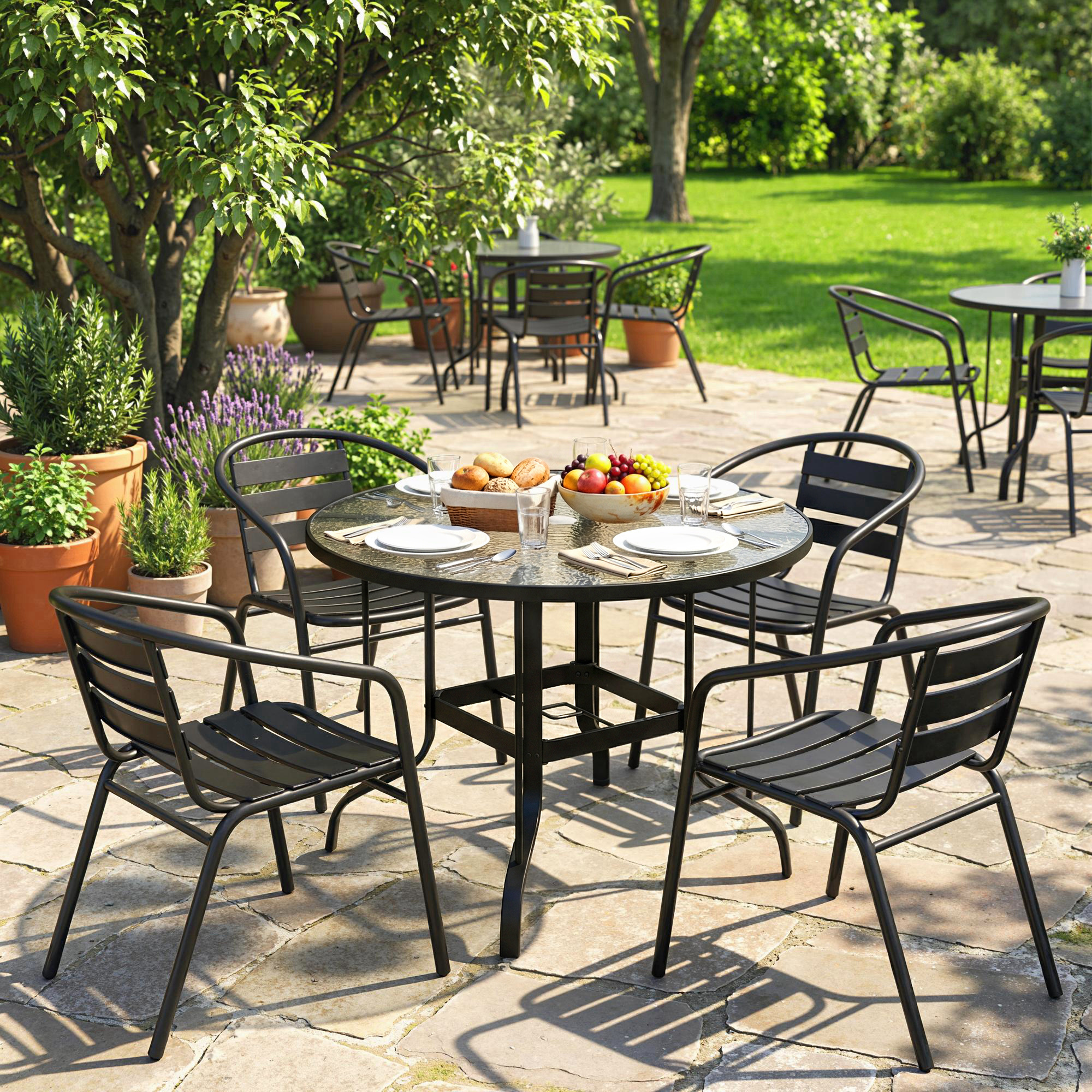 Un tavolo da giardino con quattro sedie, apparecchiato con pane, frutta e bicchieri.