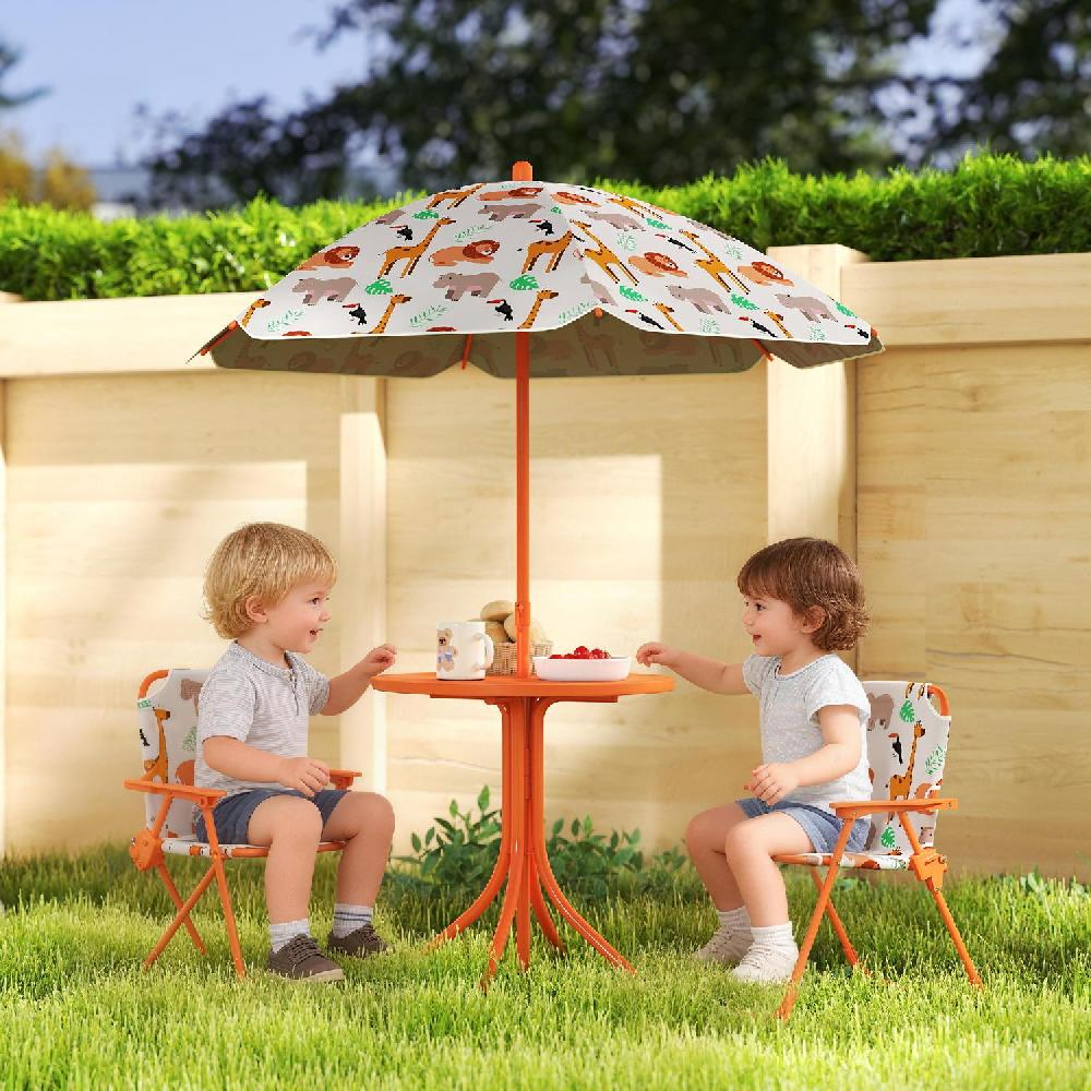 Due bambini siedono a un tavolo arancione sotto un ombrellone con stampa animale in un giardino.