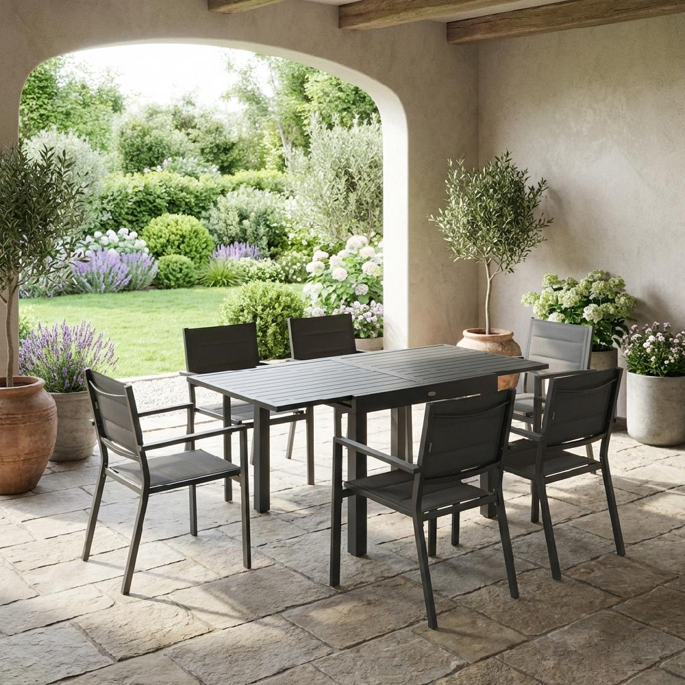 Un set da pranzo da esterno grigio scuro con sei sedie su un patio di pietra.