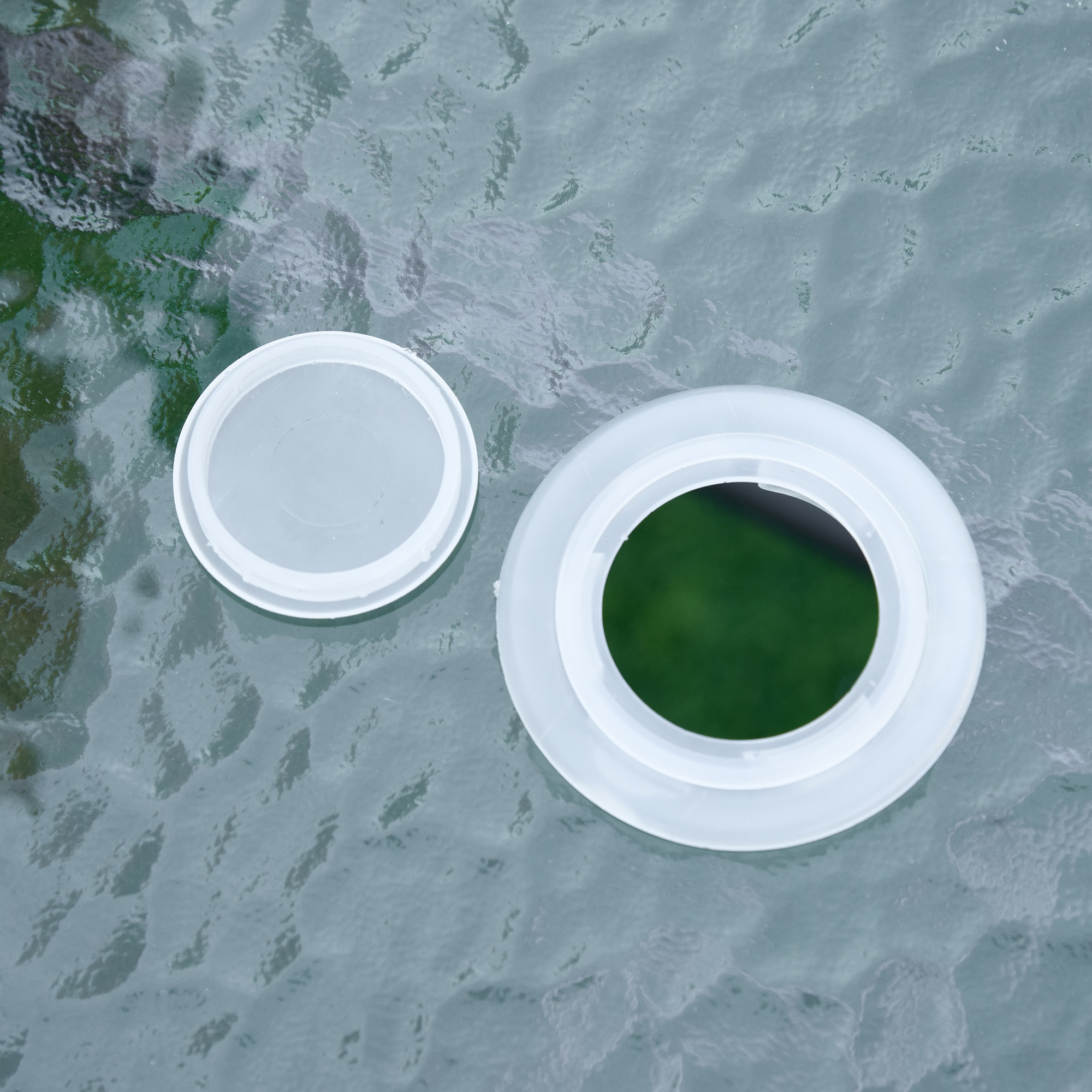 Un coperchio di plastica bianco e una cornice circolare su una superficie di vetro testurizzato.