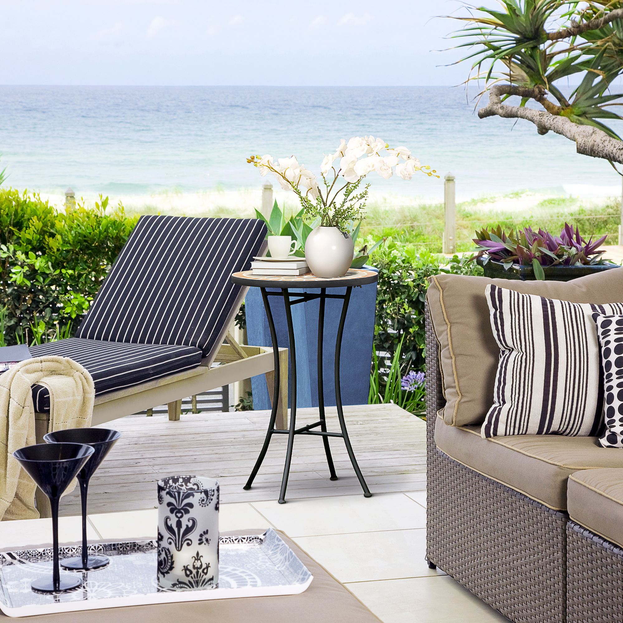 Rilassante patio sulla spiaggia con lettino, divano e tavolo vicino al mare.