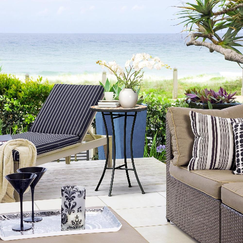 Un patio con vista sull'oceano, con lettino, tavolo, divano e decorazioni.