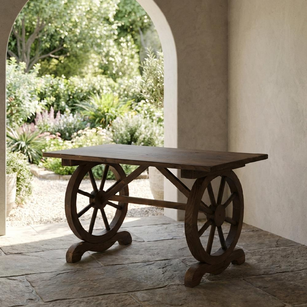 Un tavolo di legno con ruote come gambe si erge su lastre di pietra davanti a un giardino.