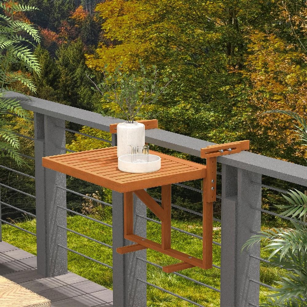 Un tavolino da balcone in legno con accessori, appeso a una ringhiera grigia.