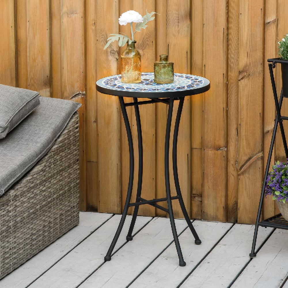 Tavolo in mosaico con due bottiglie e un fiore, su una terrazza di legno.