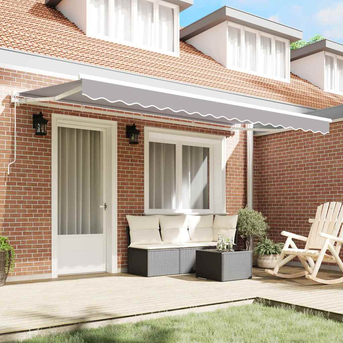 Eine graue Markise erstreckt sich über eine Ziegelterrasse mit Gartenmöbeln, darunter ein Sofa und ein Schaukelstuhl.
