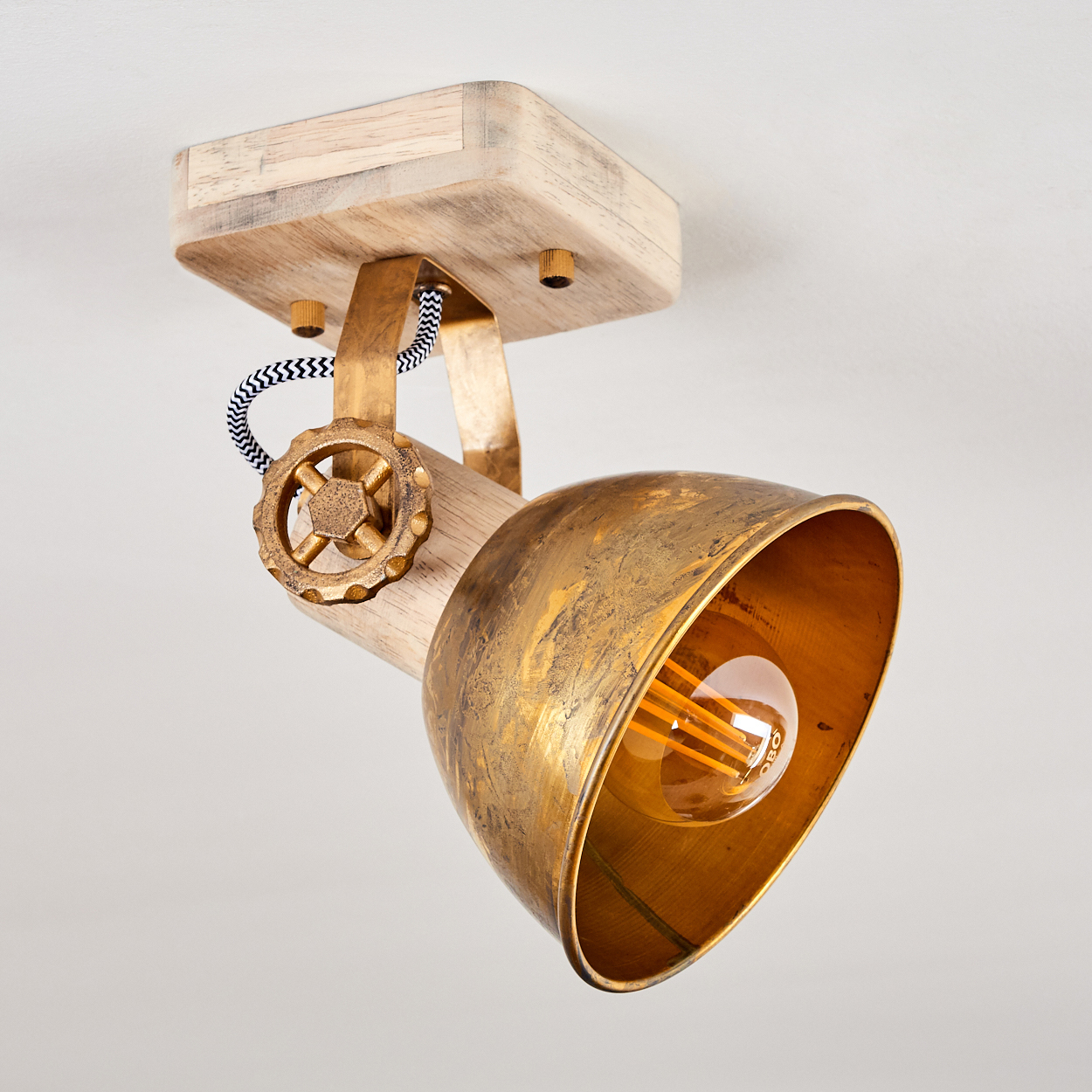 Eine antike Lampe mit Holzsockel, Messingreflektor und Glühbirne.