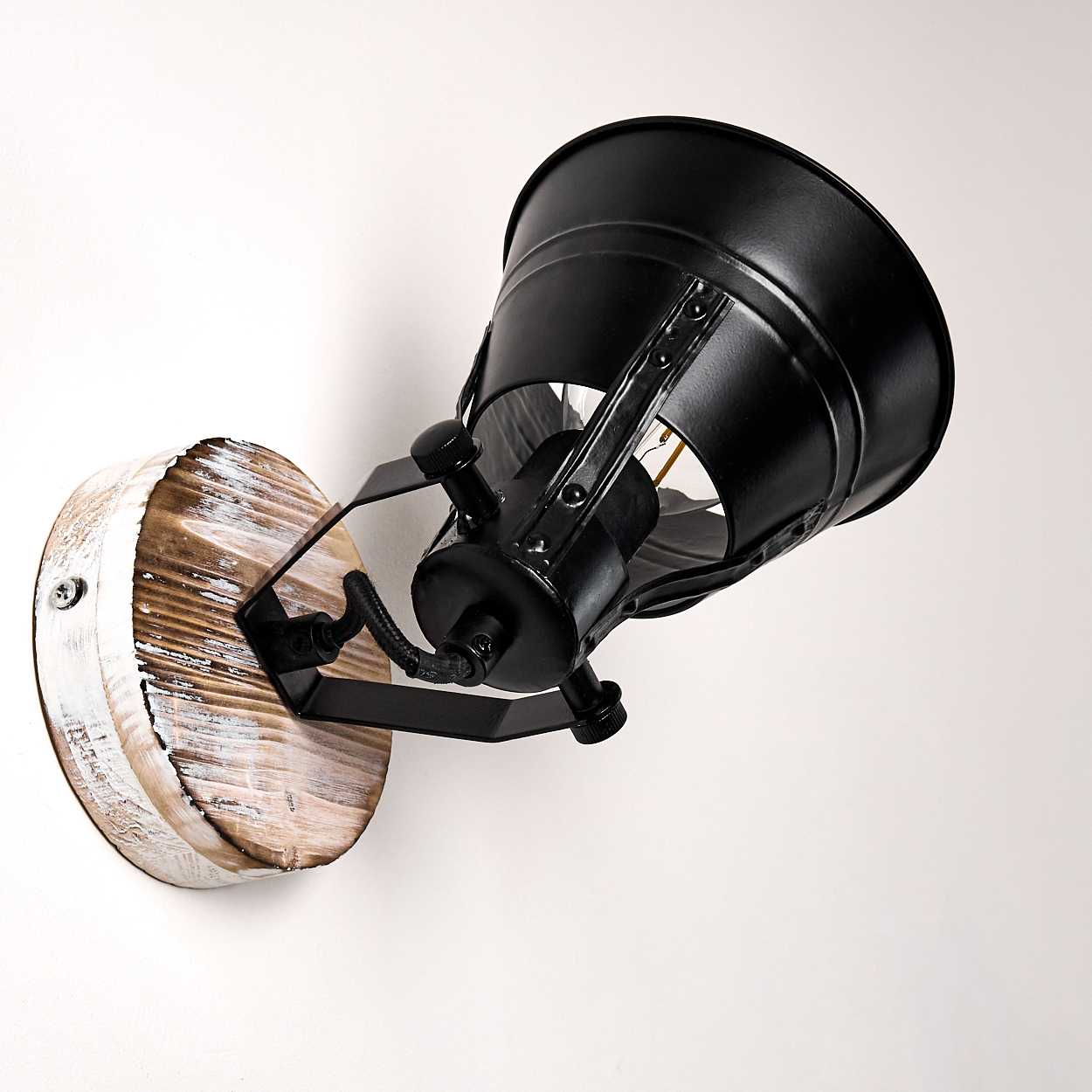 Eine schwarze Wandleuchte im Industriestil mit Holzsockel ist an einer weißen Wand montiert.