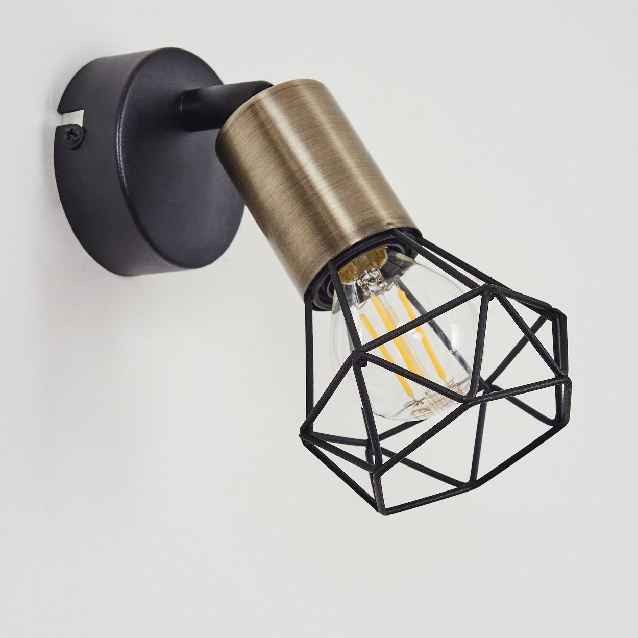 Schwarze Wandlampe mit Messingakzent, industriellem Käfigdesign und Edison-Glühbirne.