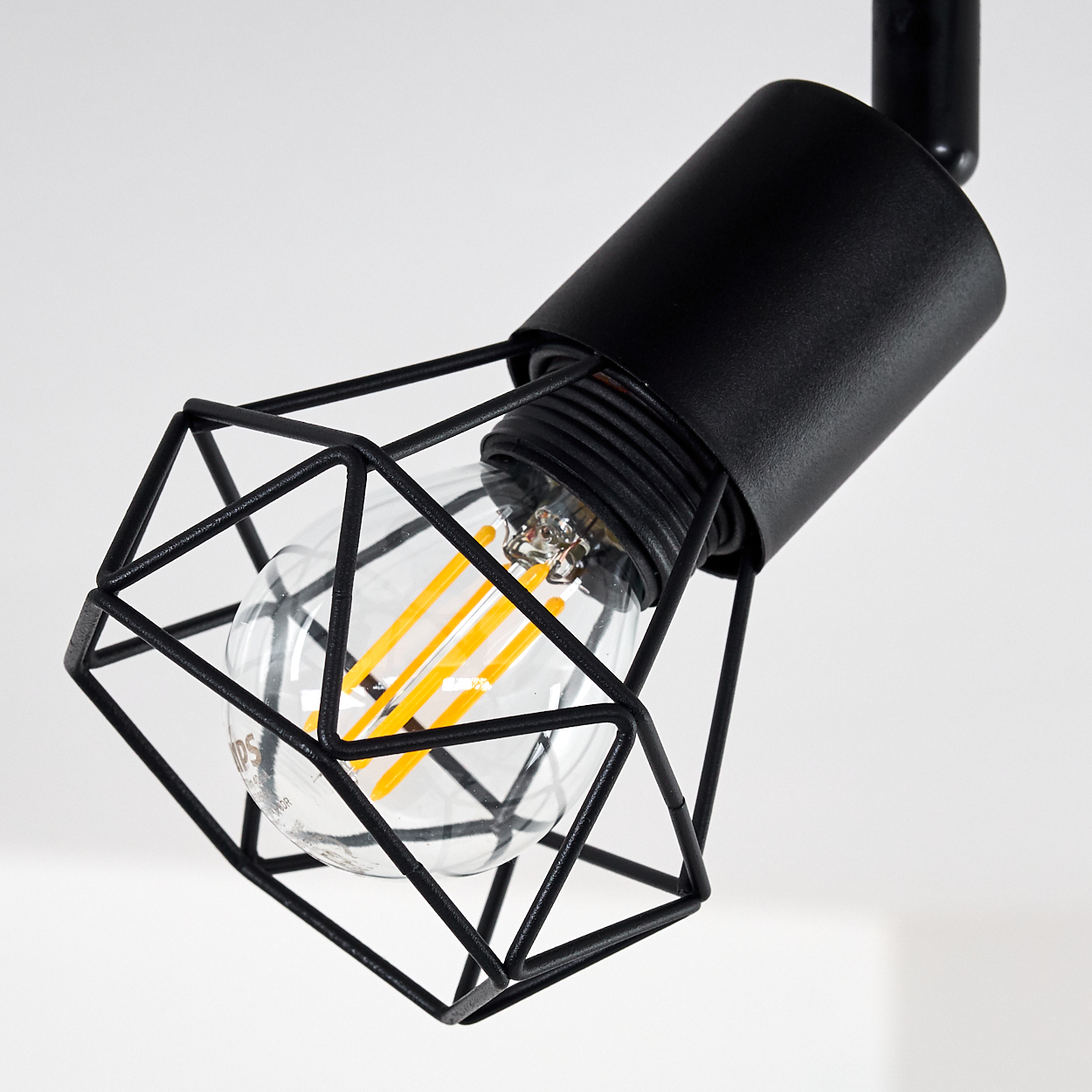 Ein schwarzer Metallkäfig umgibt eine klare Edison-Glühbirne mit orangen Glühfäden.