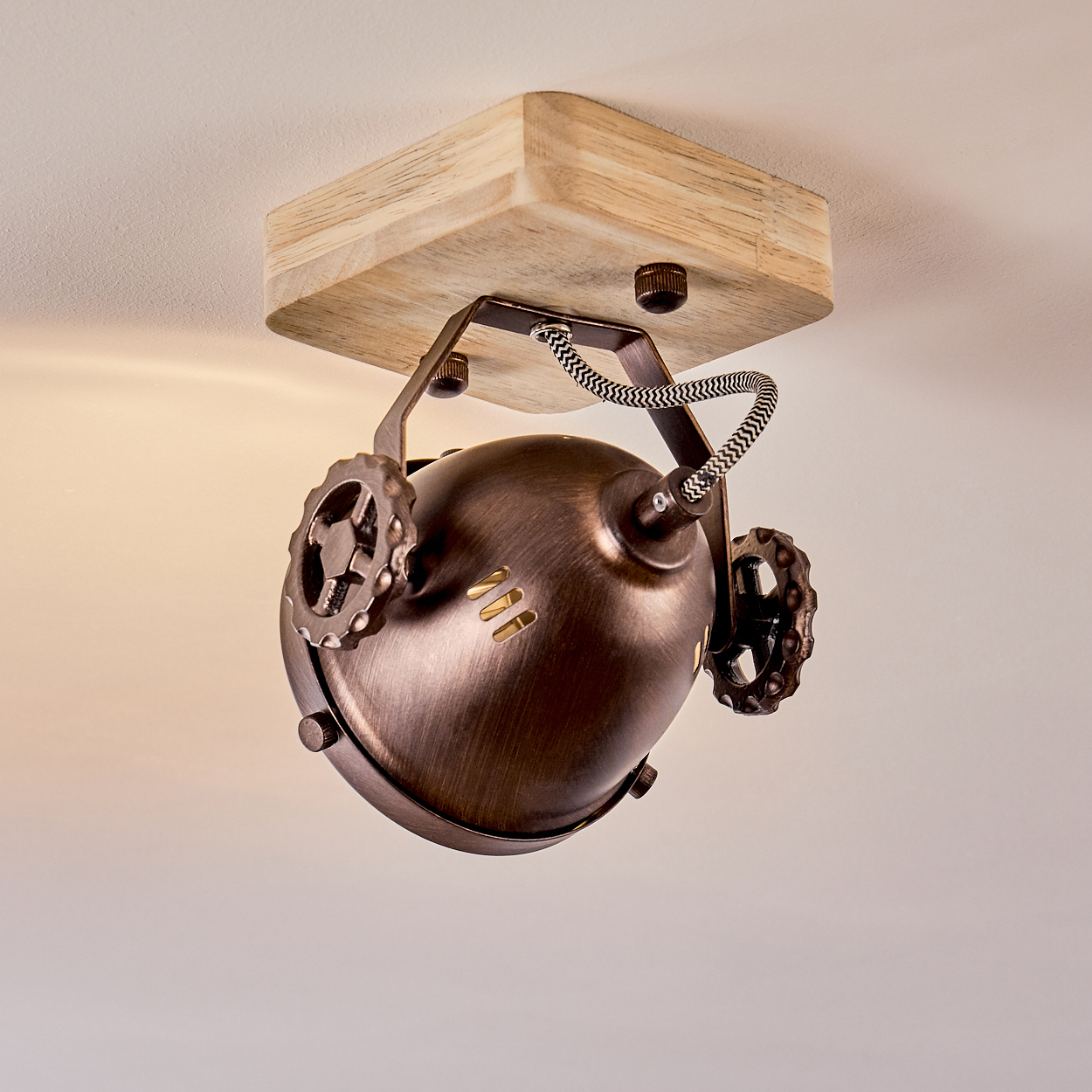 Eine Deckenleuchte im Steampunk-Stil mit Holzsockel und kupferfarbener Lampe.