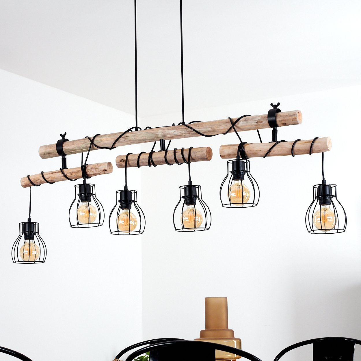 Holz-Kronleuchter mit sechs Käfiglampen und Glühbirnen, der von der Decke hängt.