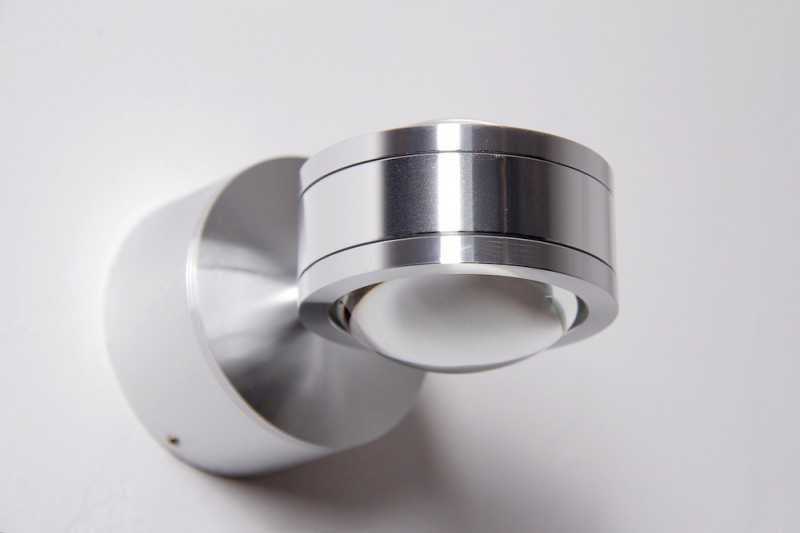 Eine silberne Wandleuchte mit kugelförmigem Lampenschirm und Metallakzenten.