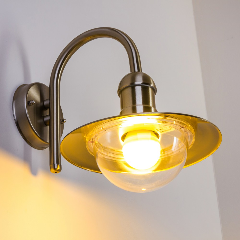 Eine Wandleuchte mit gebogenem Arm und Glaskuppel leuchtet hell.