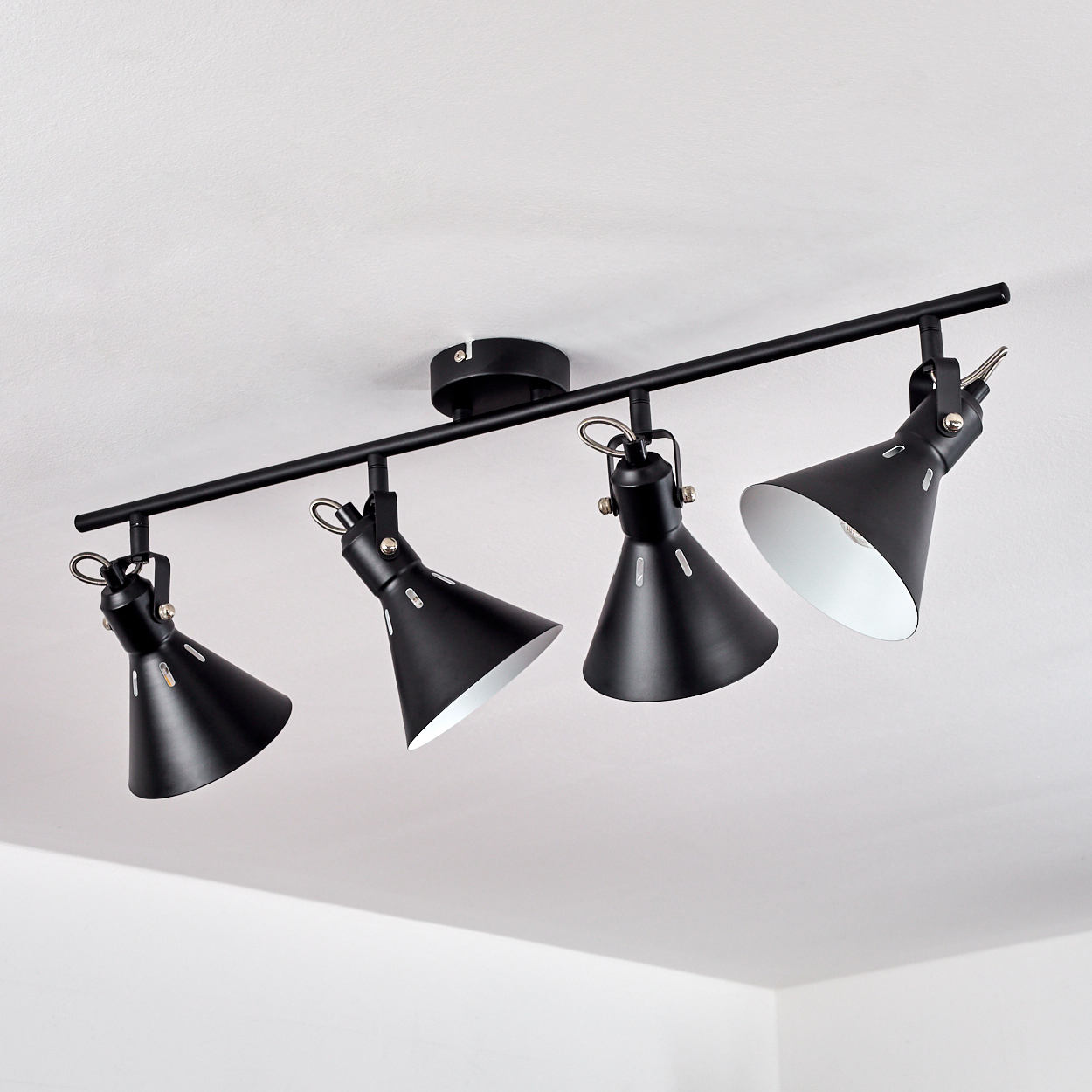 Eine schwarze Deckenleuchte mit vier Spots und verstellbaren Lampen in Kegelform.