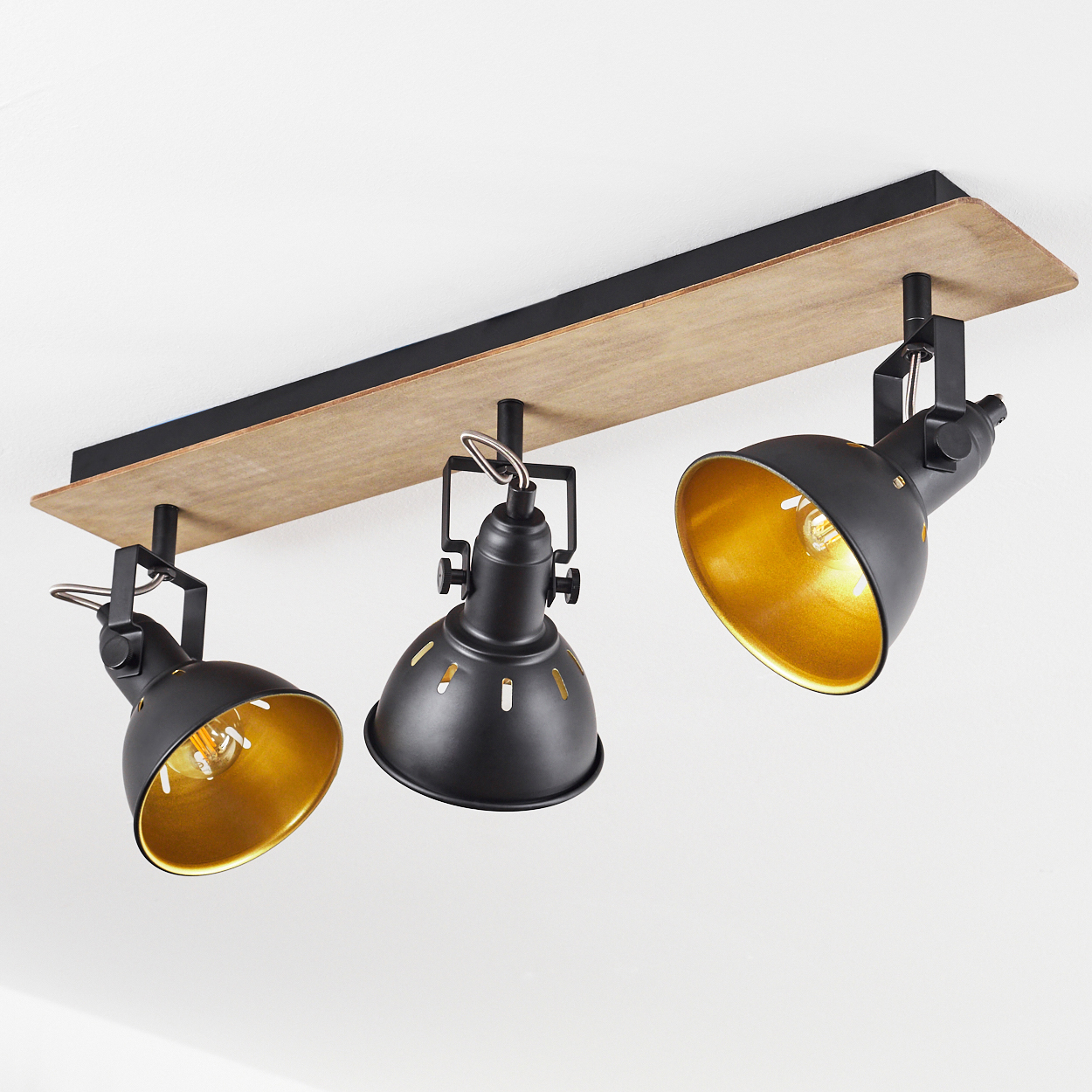 Schwarzer Deckenstrahler mit Holzsockel und drei verstellbaren Lampen mit goldenem Innenschirm.