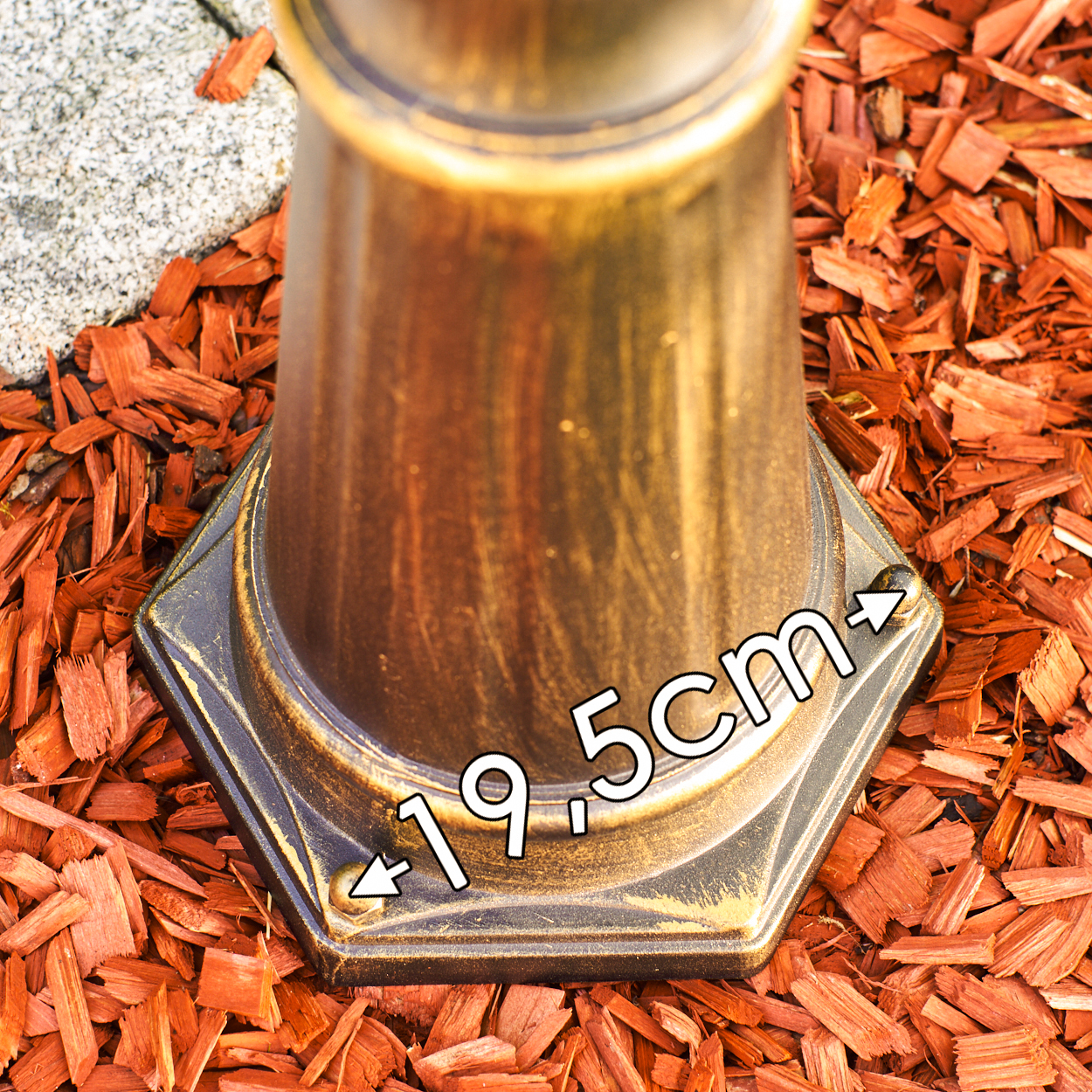 Ein bronzefarbener Sockel mit der Aufschrift 19,5 cm auf rotem Mulch.