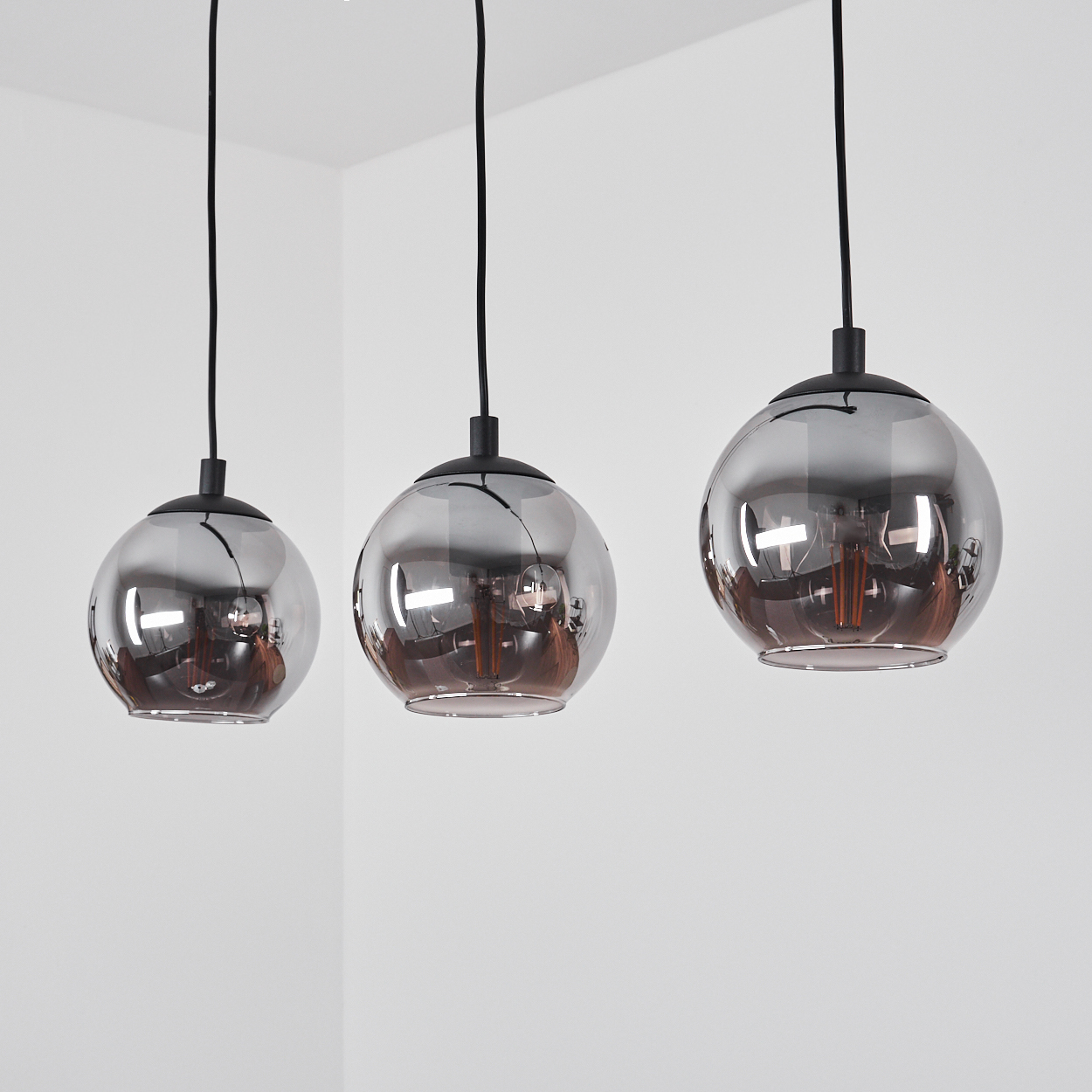 Drei kugelförmige Pendelleuchten mit rauchigem Glas und sichtbaren Glühbirnen.