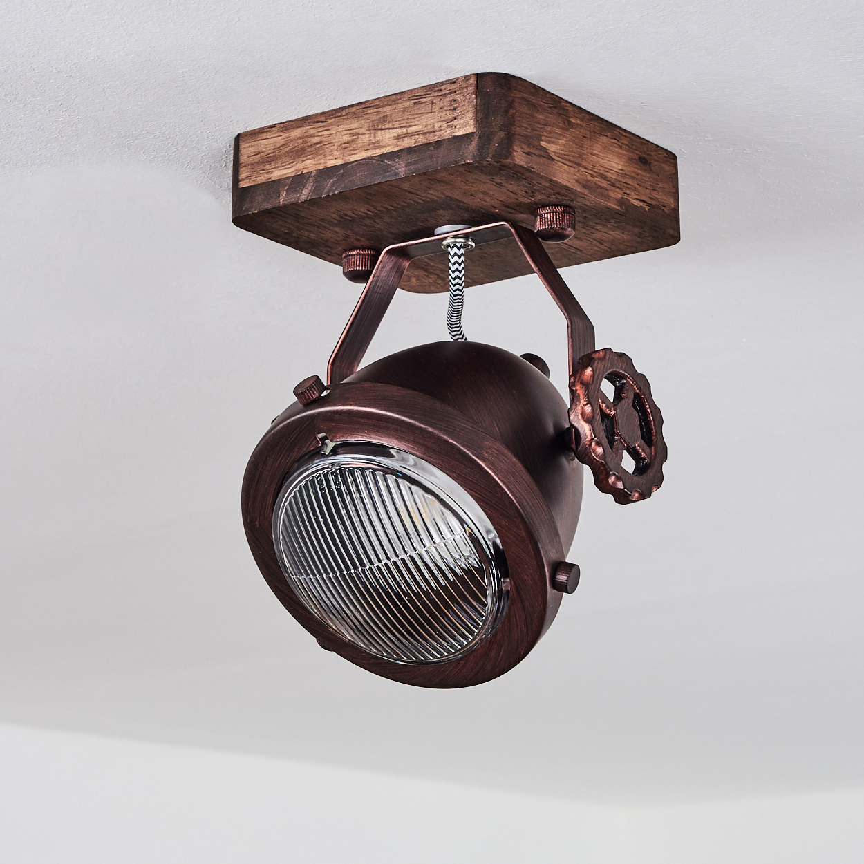 Eine kupferfarbene Lampe mit Holzbasis hängt von der Decke.