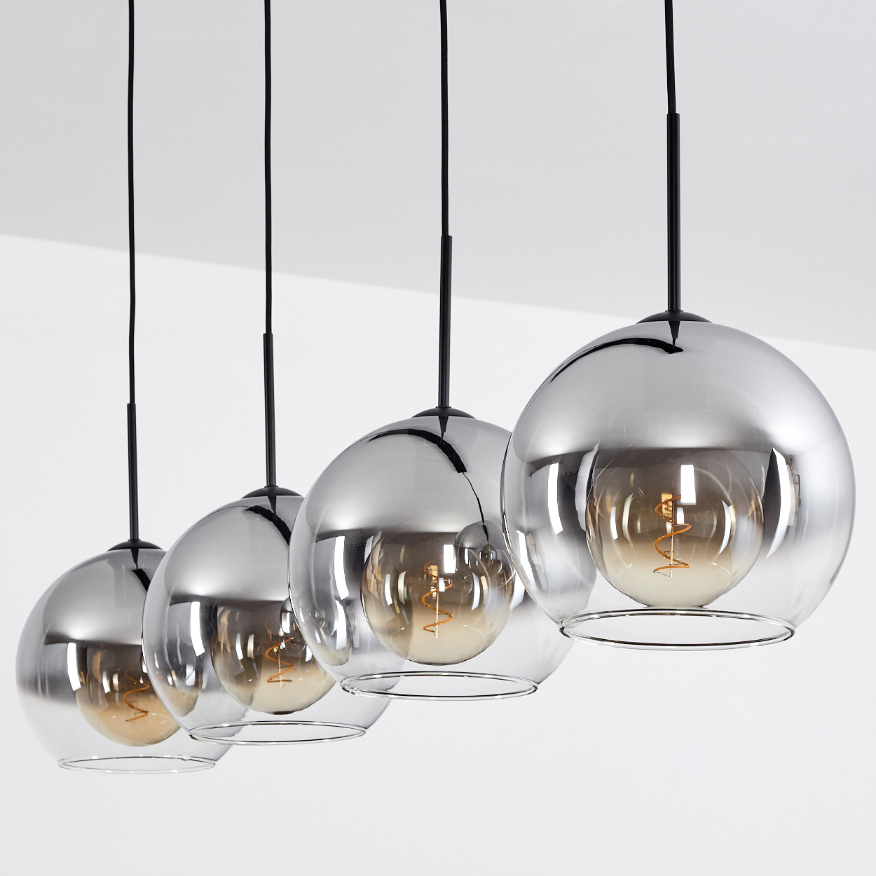 Vier moderne Pendelleuchten mit kugelförmigen Chromschirmen und sichtbaren Edison-Glühbirnen.