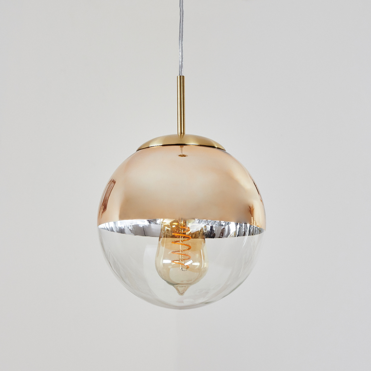 Eine kugelförmige Pendelleuchte mit goldener Oberseite und klarem Glas unten.