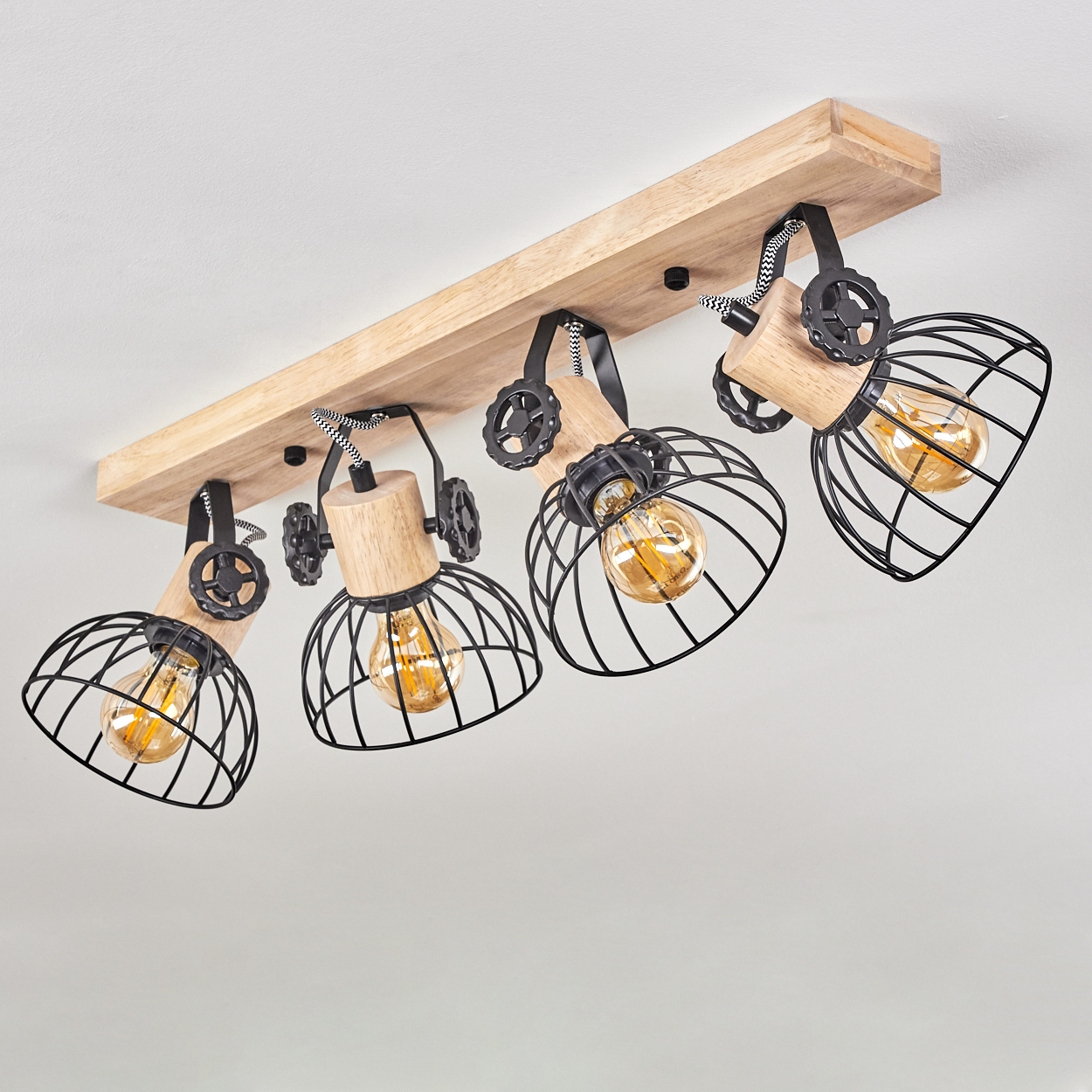 Eine Holzleiste mit vier schwarzen Metallkäfigleuchten im Industriestil, jede mit sichtbarer Edison-Glühbirne.