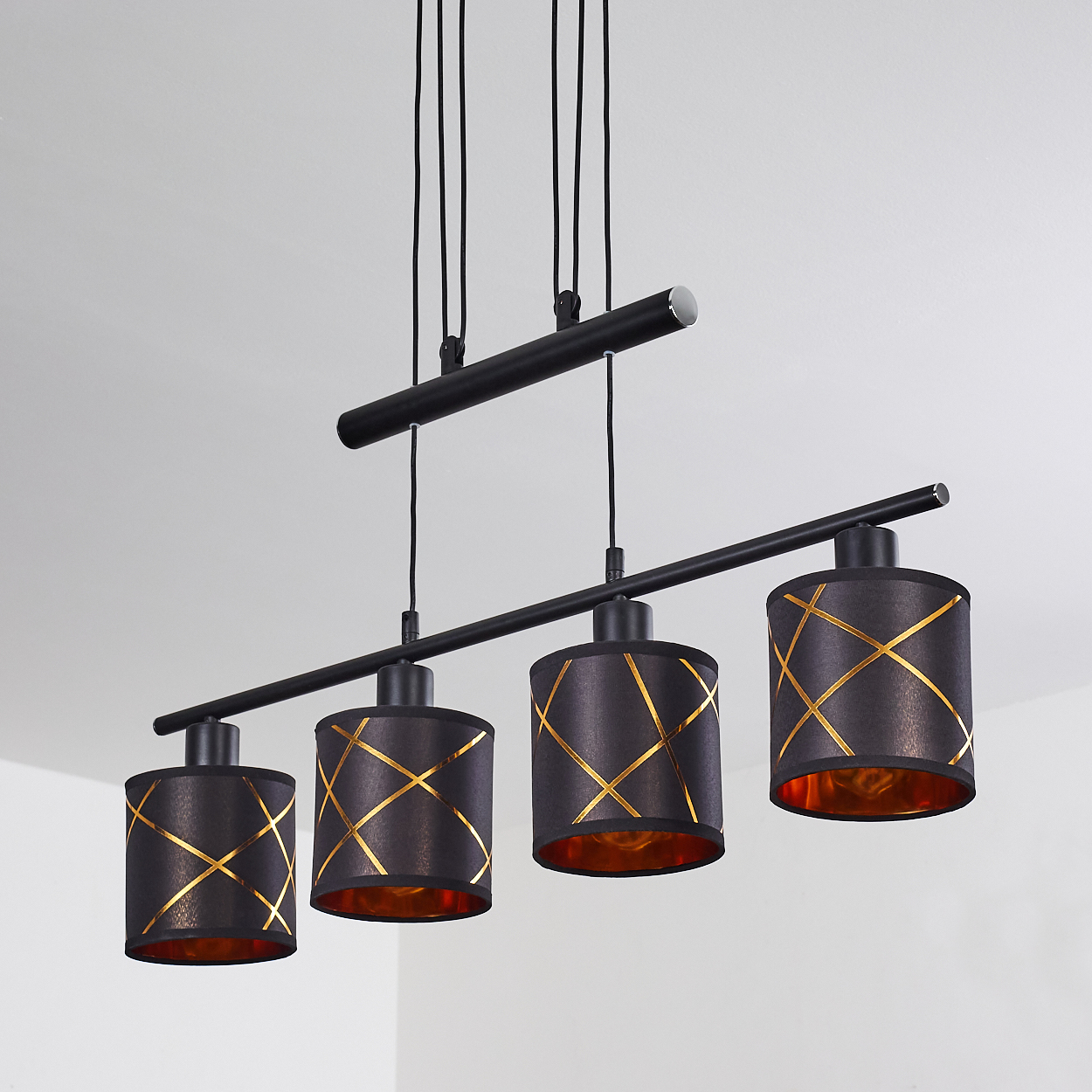 Eine schwarze Pendelleuchte mit vier Lampenschirmen und goldenen Kreuzmustern.