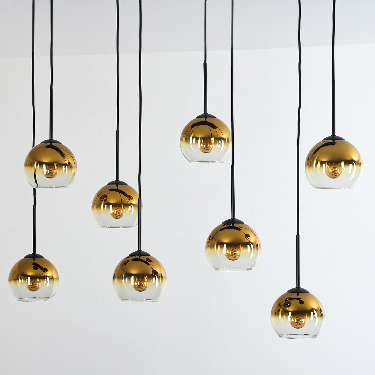 Acht goldene Pendelleuchten mit Glaskugeln auf weißem Hintergrund.
