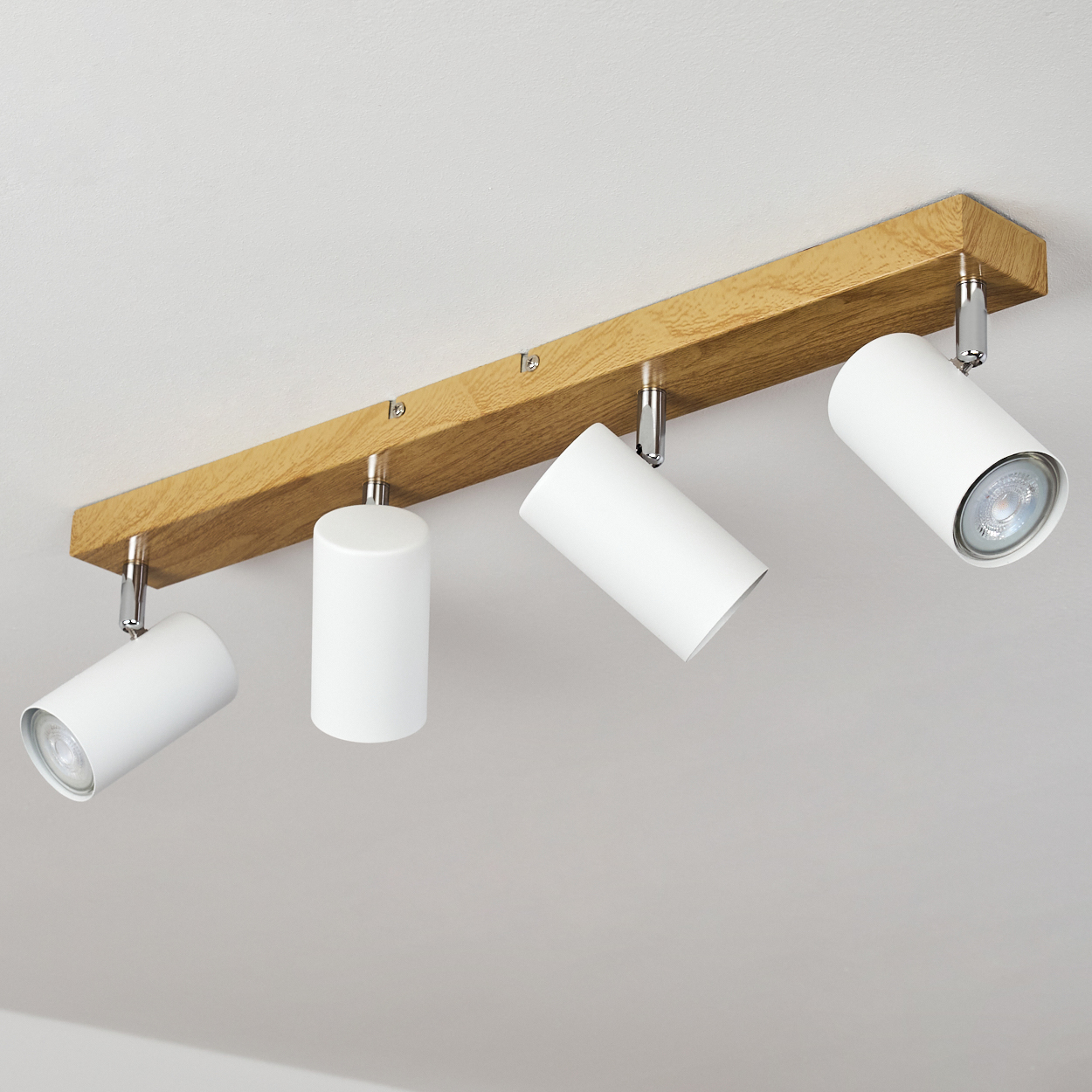 Deckenleuchte mit vier weißen Zylindern auf einem Holzsockel.