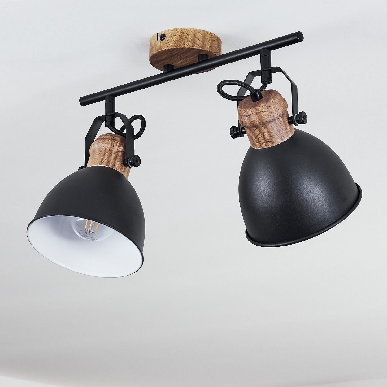 Zwei schwarze Lampenschirme mit Holzdetails an einer schwarzen Schiene, an einer Decke montiert.