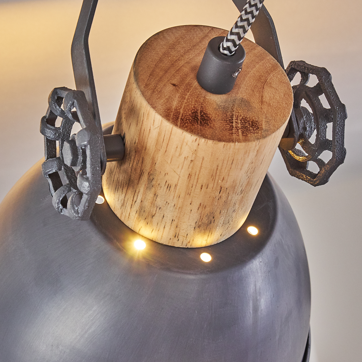 Nahaufnahme einer rustikalen Industrie-Pendelleuchte mit Holz, Metall und Zierrädern.