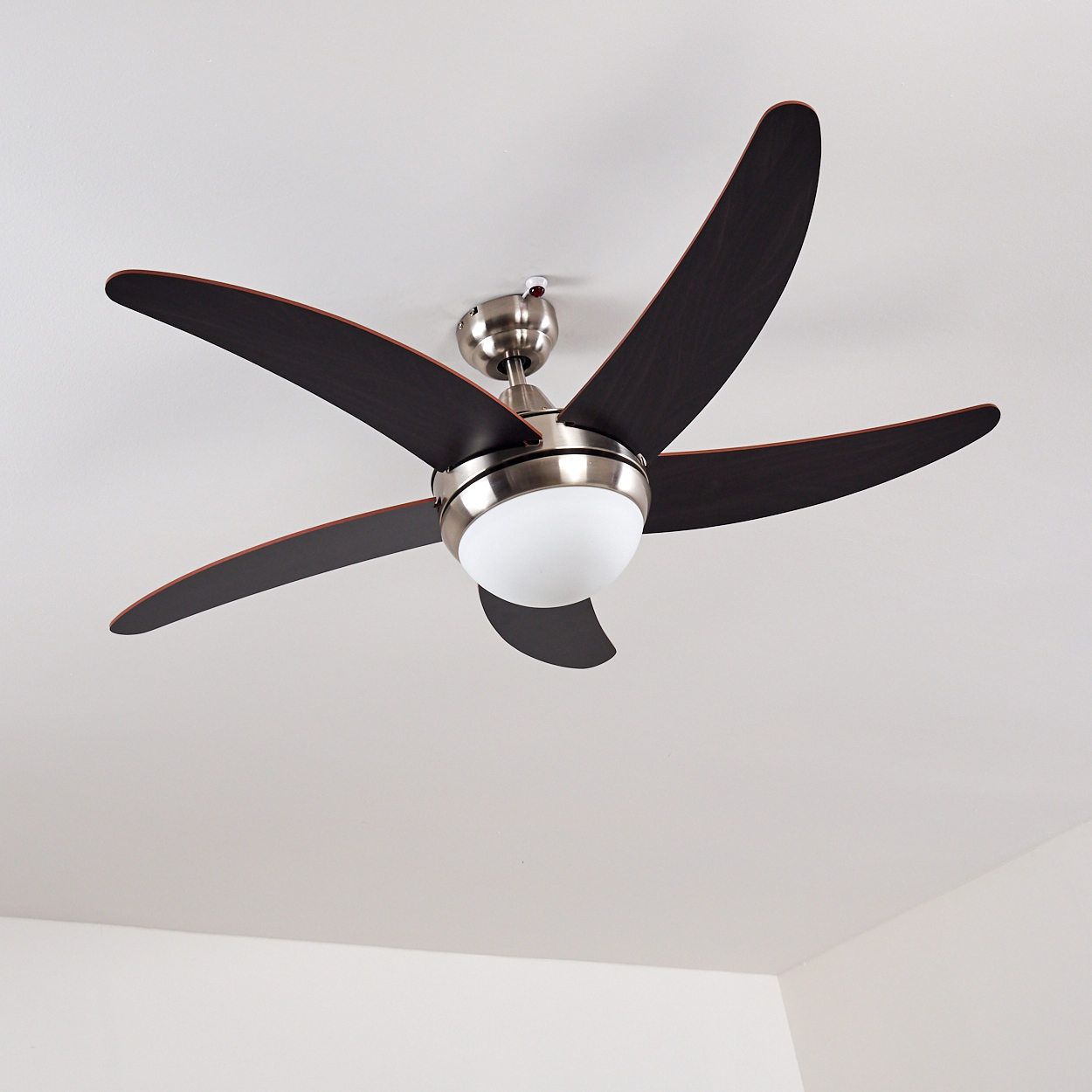 Deckenventilator mit fünf dunklen Rotorblättern und einer runden Leuchte.