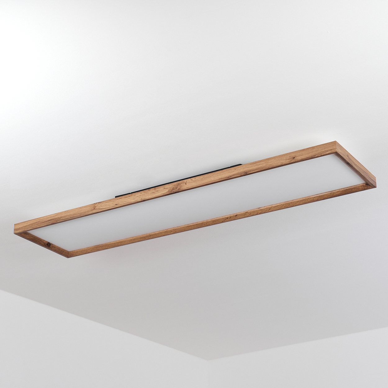 Rechteckige Deckenleuchte mit Holzrahmen und mattiertem Glasdiffusor, an weißer Decke montiert.