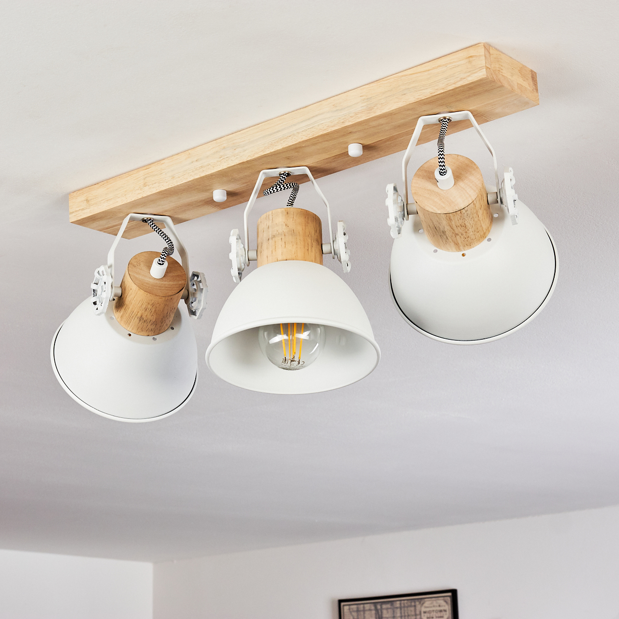 Deckenleuchte mit drei weißen Schirmen und Holzakzenten an einem Holzträger.